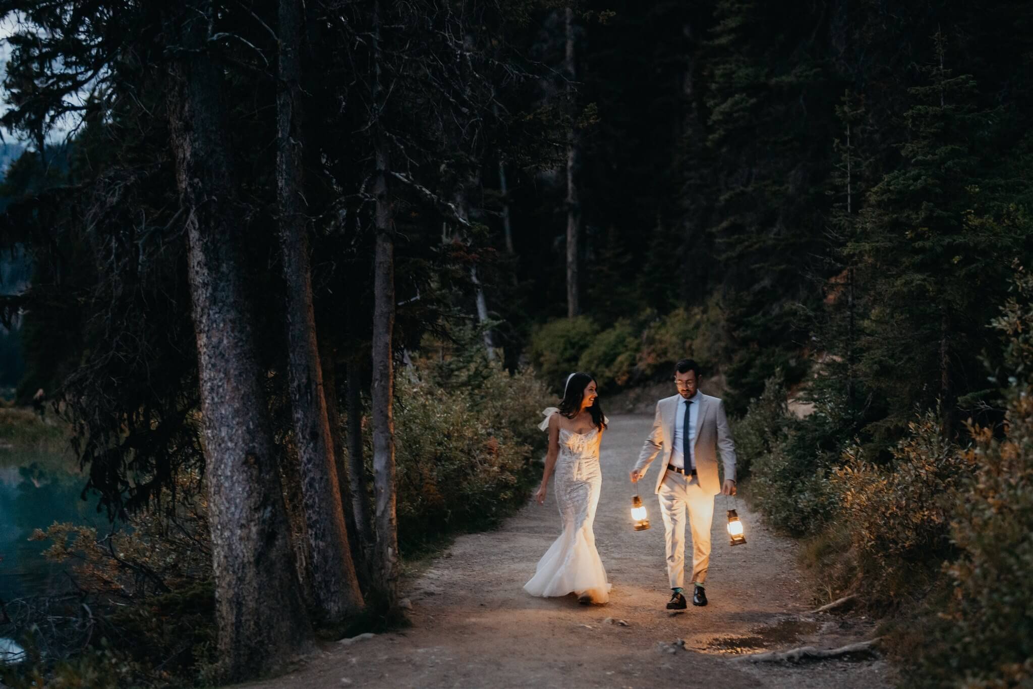 Bride and groom holding lanterns by Lake Louise at their luxury wedding at Fairmont Chateau Lake Louise hotel