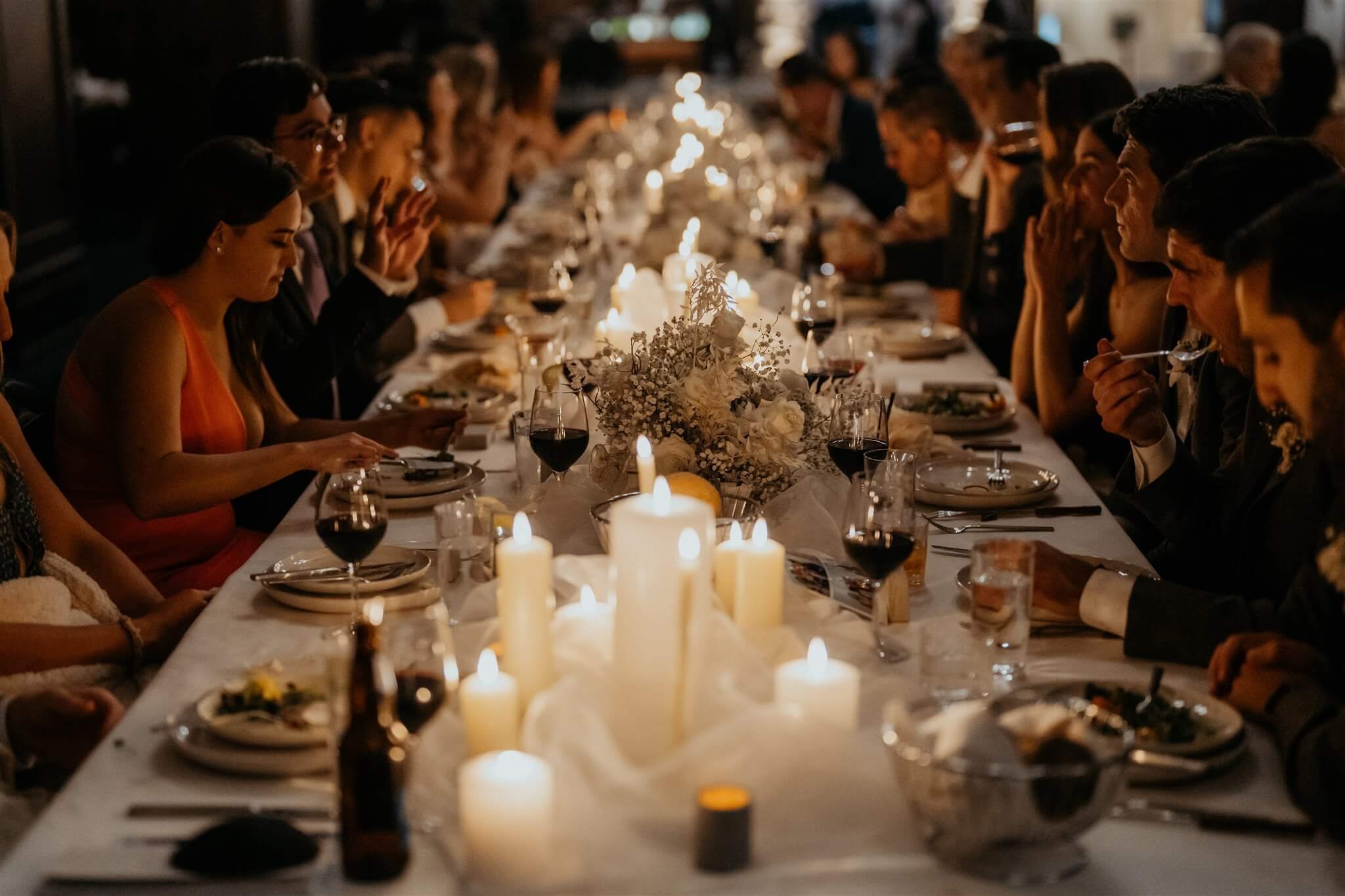 Guests eat a wedding reception tables with white and gold wedding decorations 
