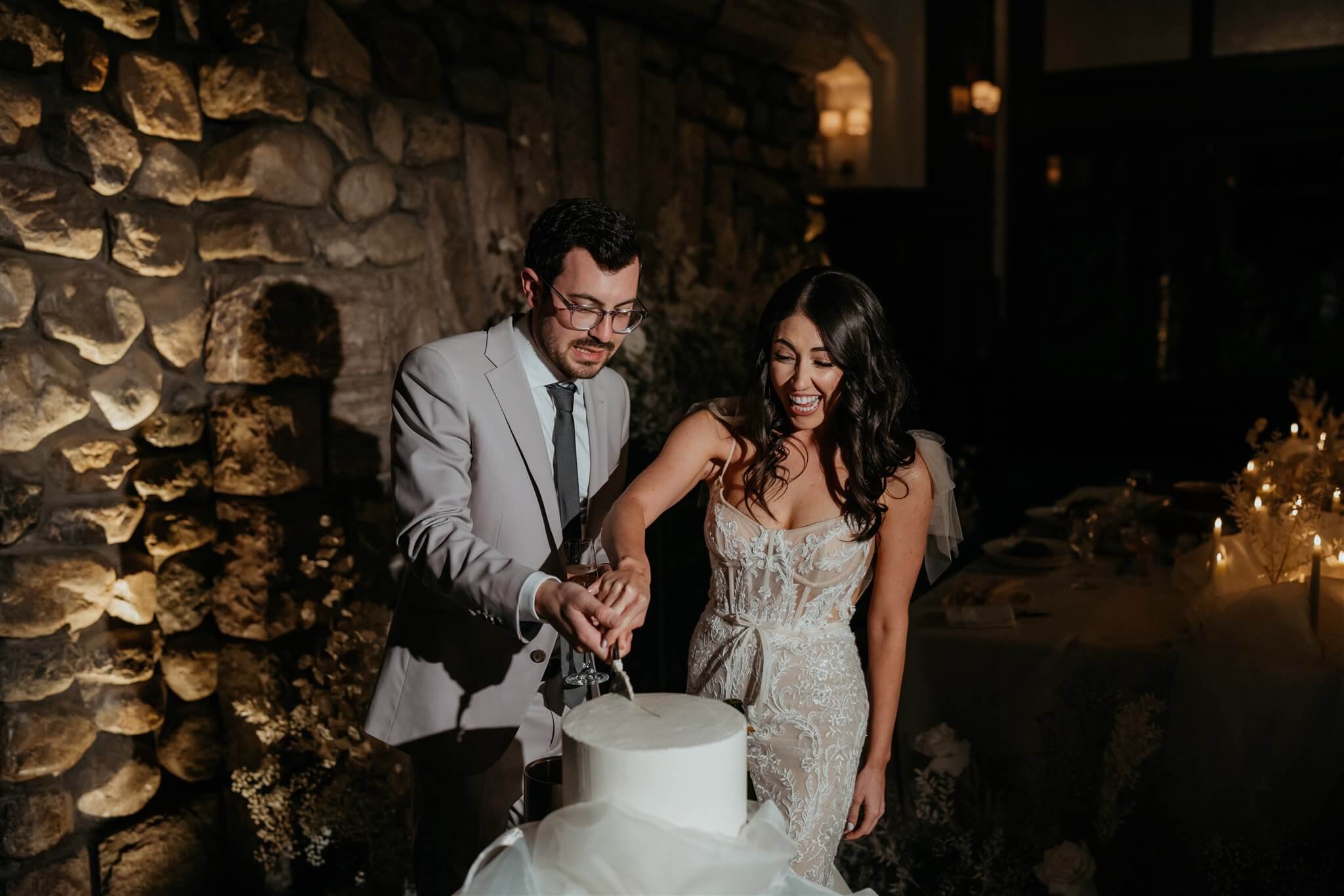 Bride and groom cut into white wedding cake at Lake Louise wedding 