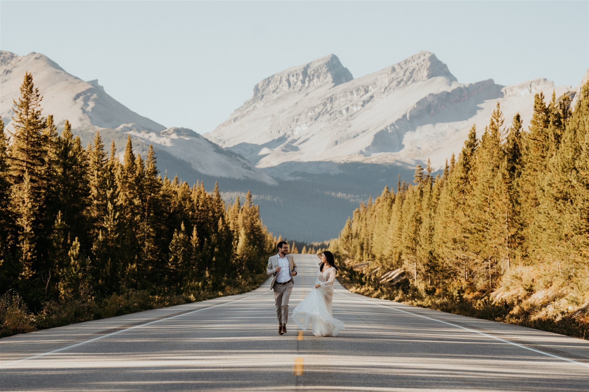 Bride and groom running down a street during their Banff elopement adventure session