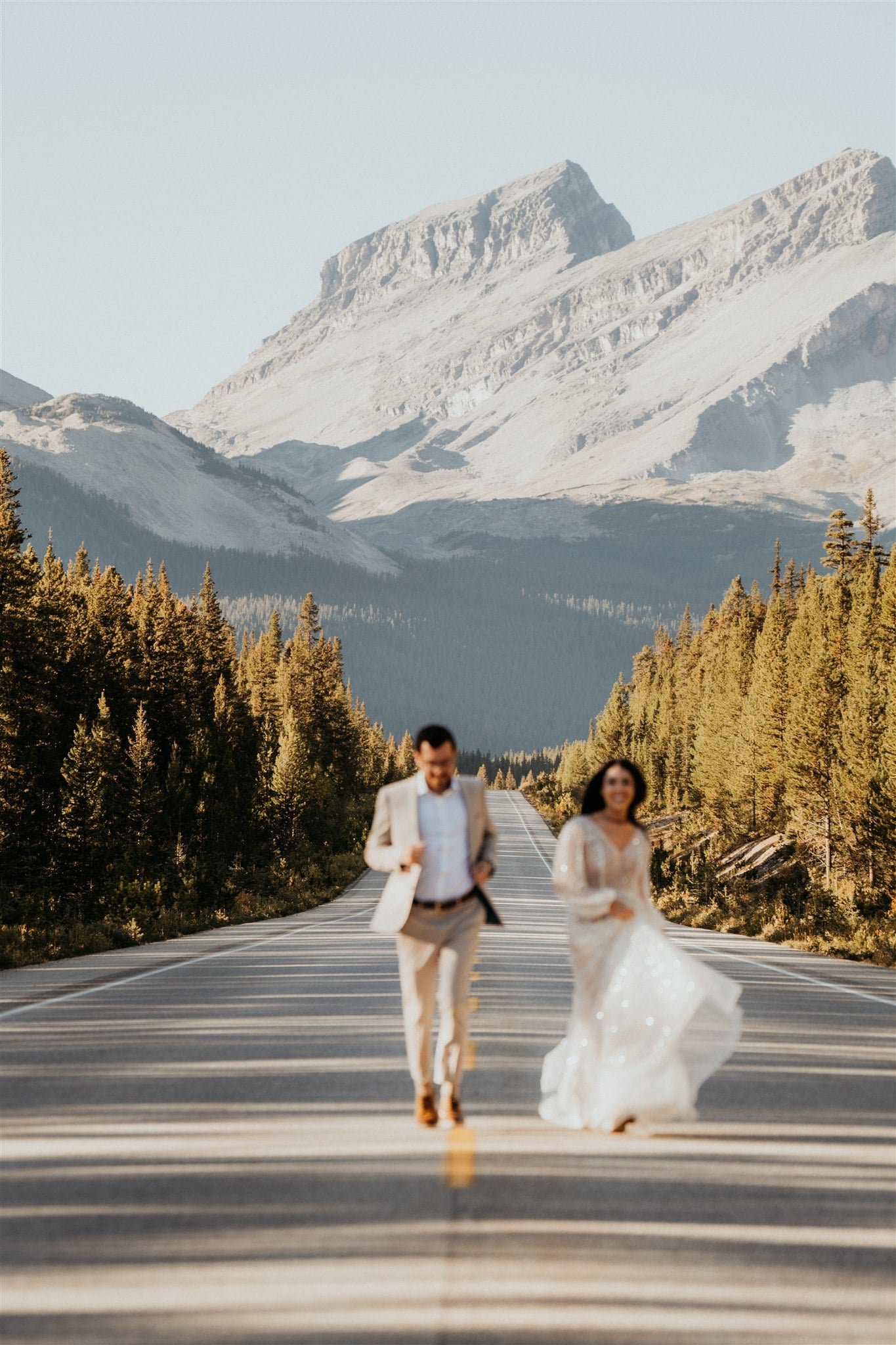 Bride and groom running down a street during their Banff elopement adventure session