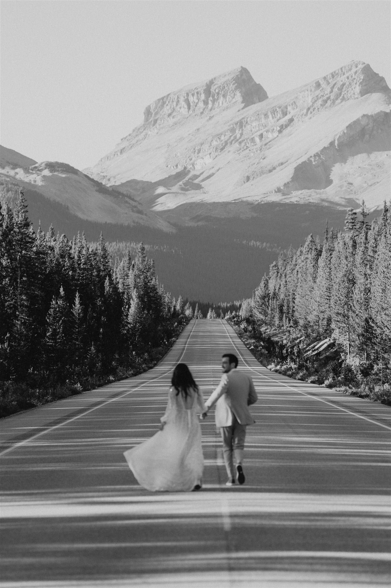 Bride and groom running down a street during their Banff elopement adventure session