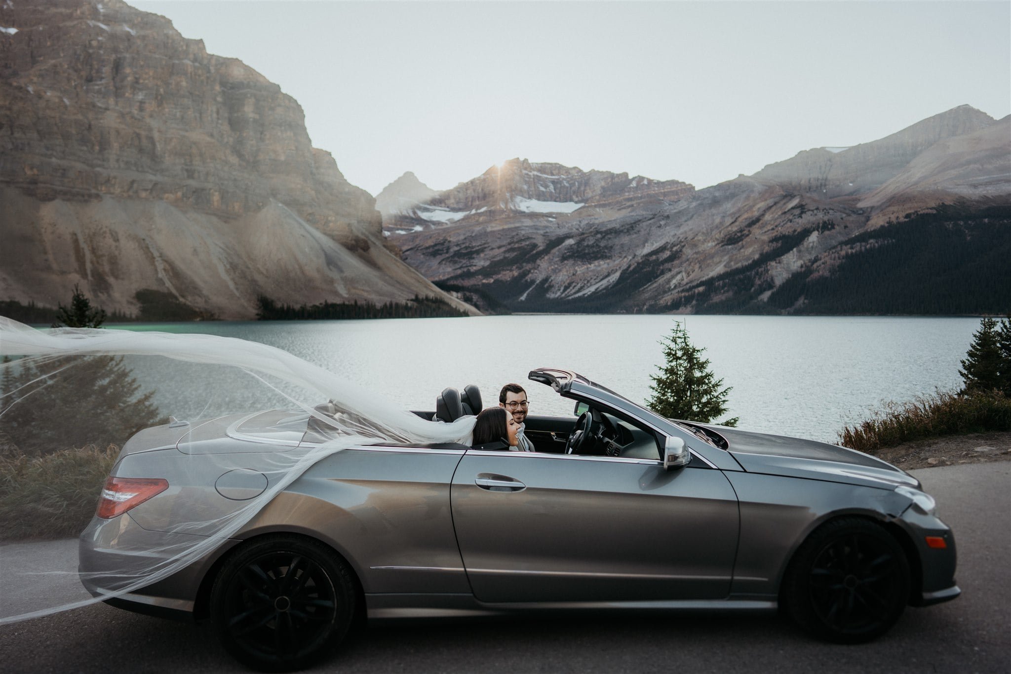 Bride and groom driving in a luxury car during their adventure elopement session in Alberta Canada
