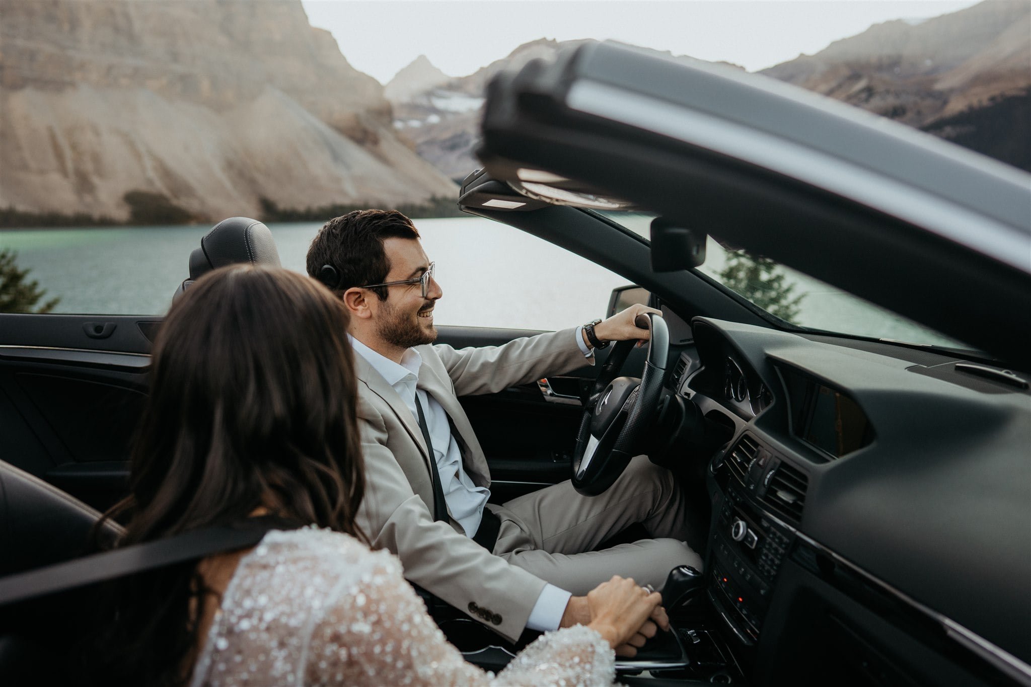 Bride and groom driving in a luxury convertible during their adventure elopement session in Alberta Canada