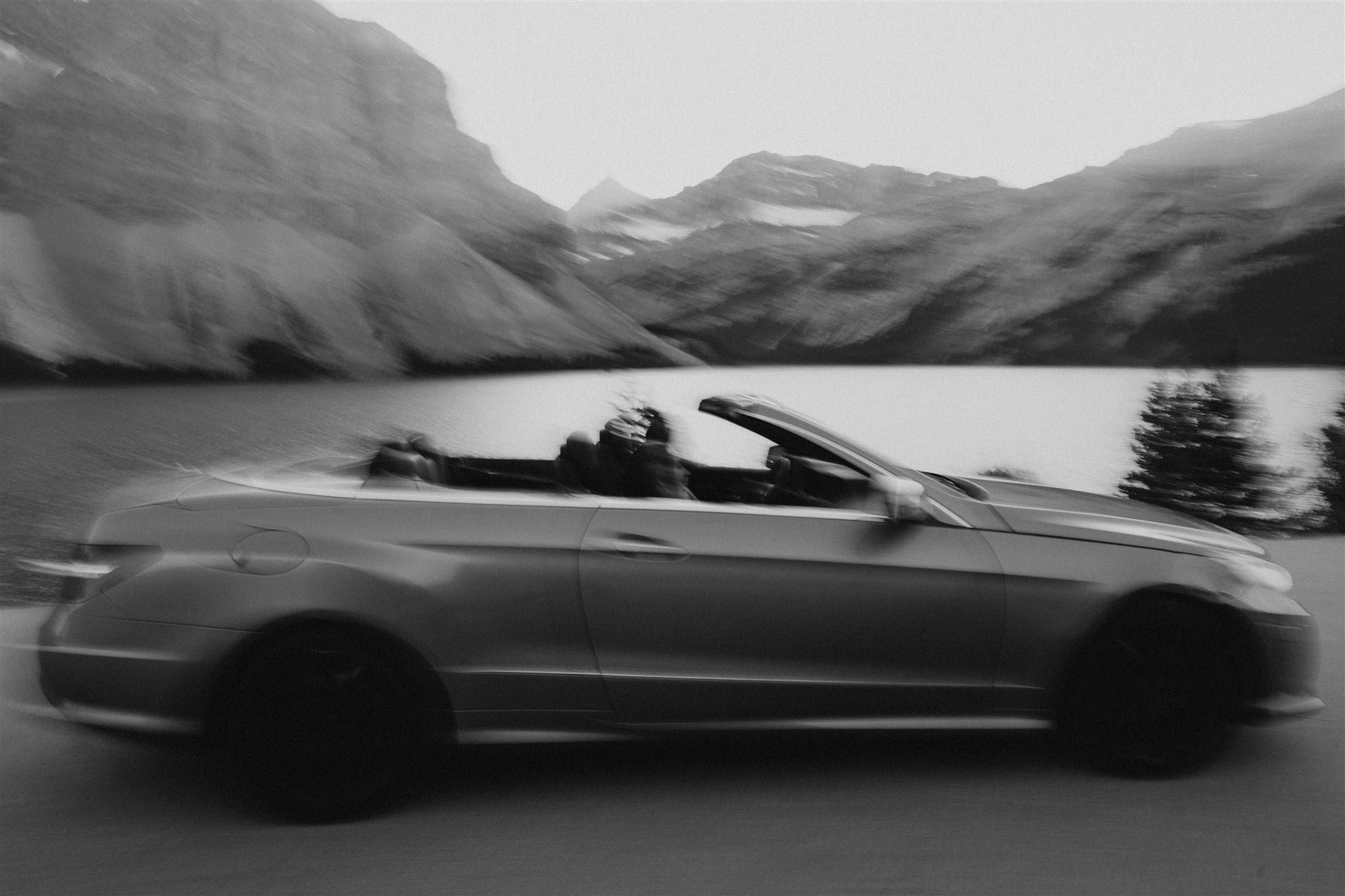 Bride and groom driving in a luxury convertible during their adventure elopement session in Alberta Canada