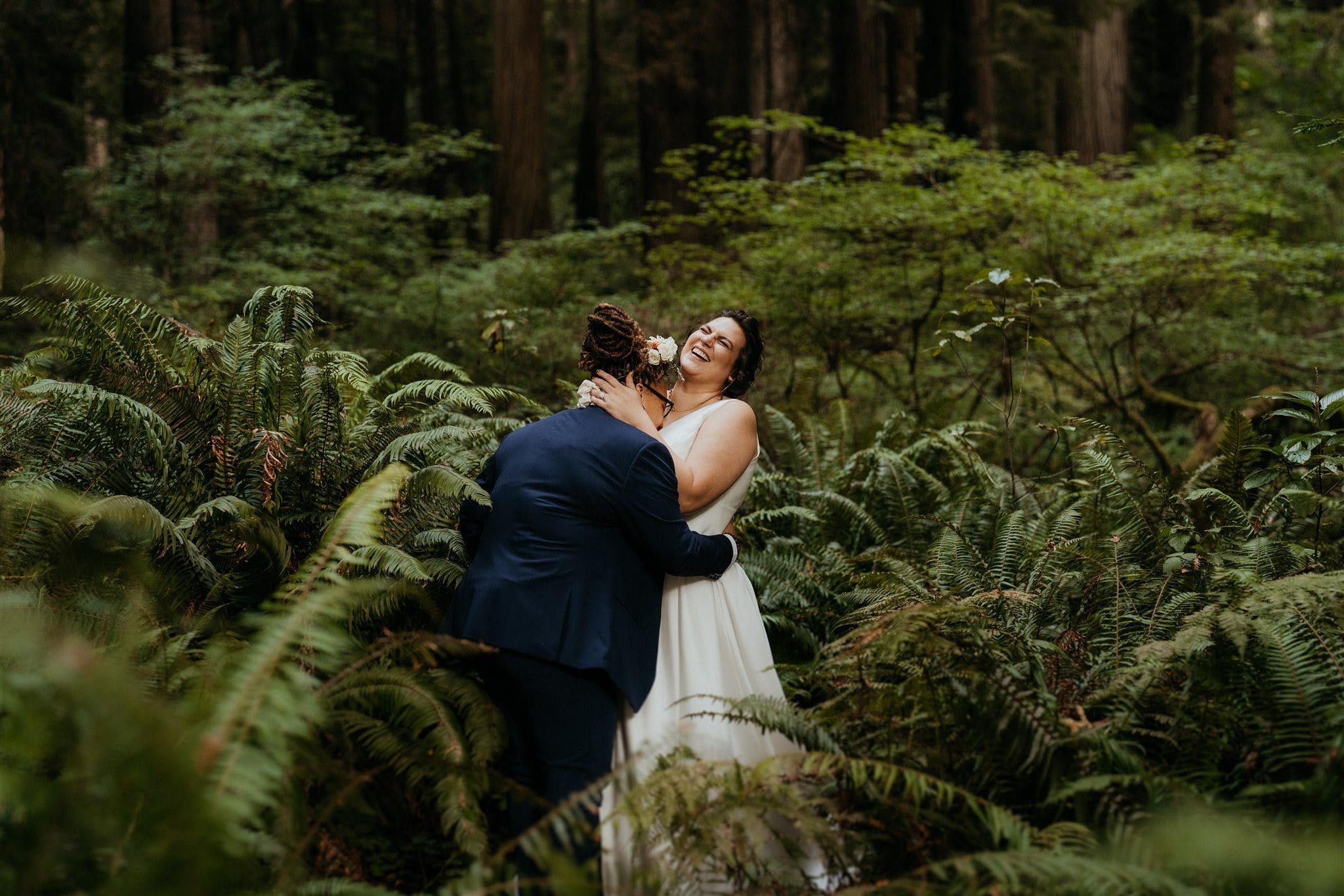 Brides laugh during forest elopement portraits on the Southern Oregon Coast