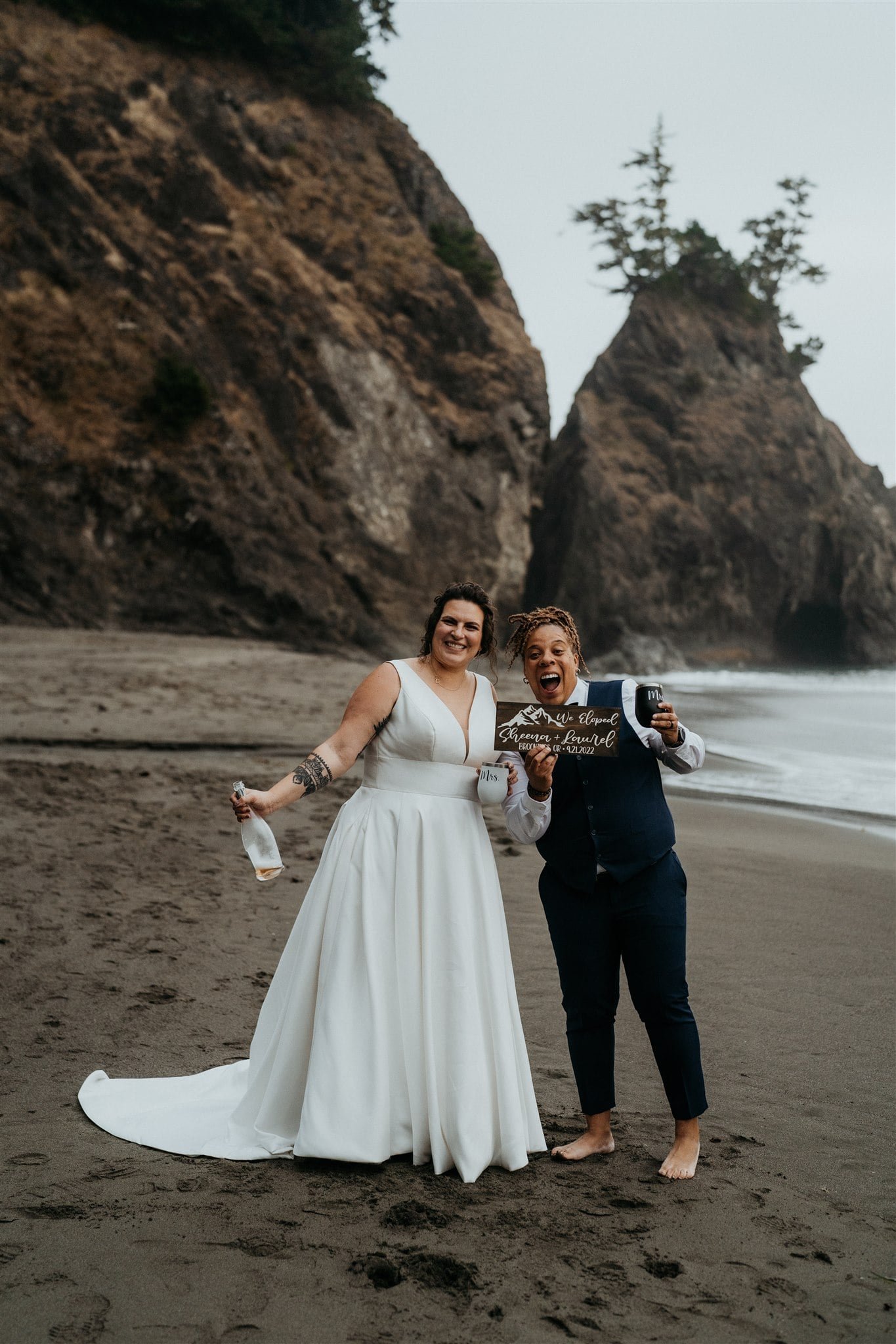 Brides hold champagne and custom sign that says "We eloped"