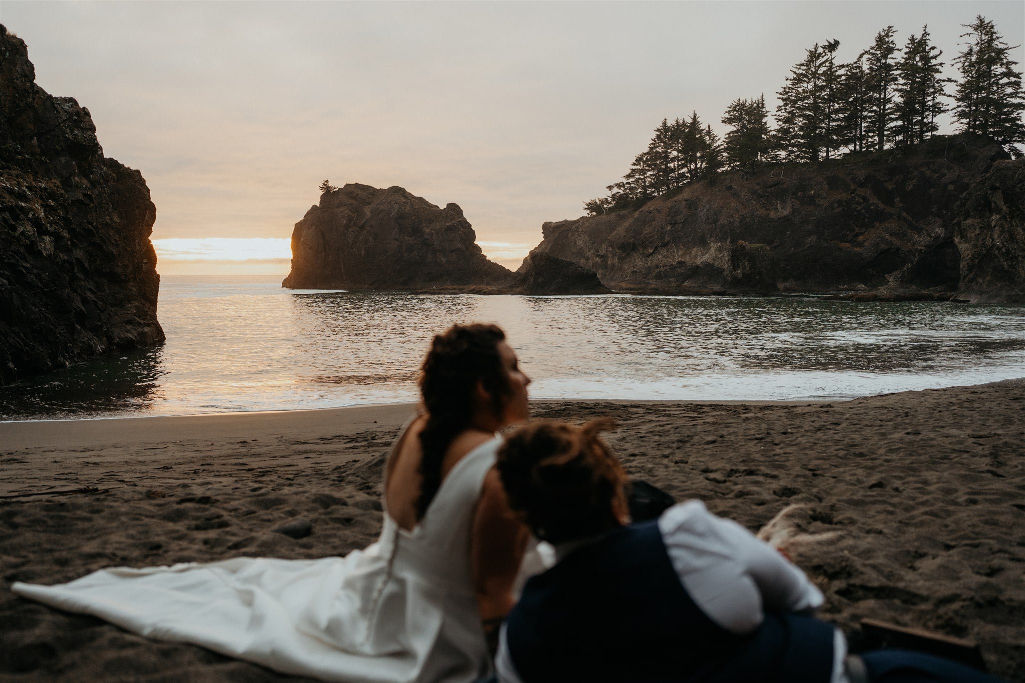 Two brides lounging on the beach during their Southern Oregon Coast elopement