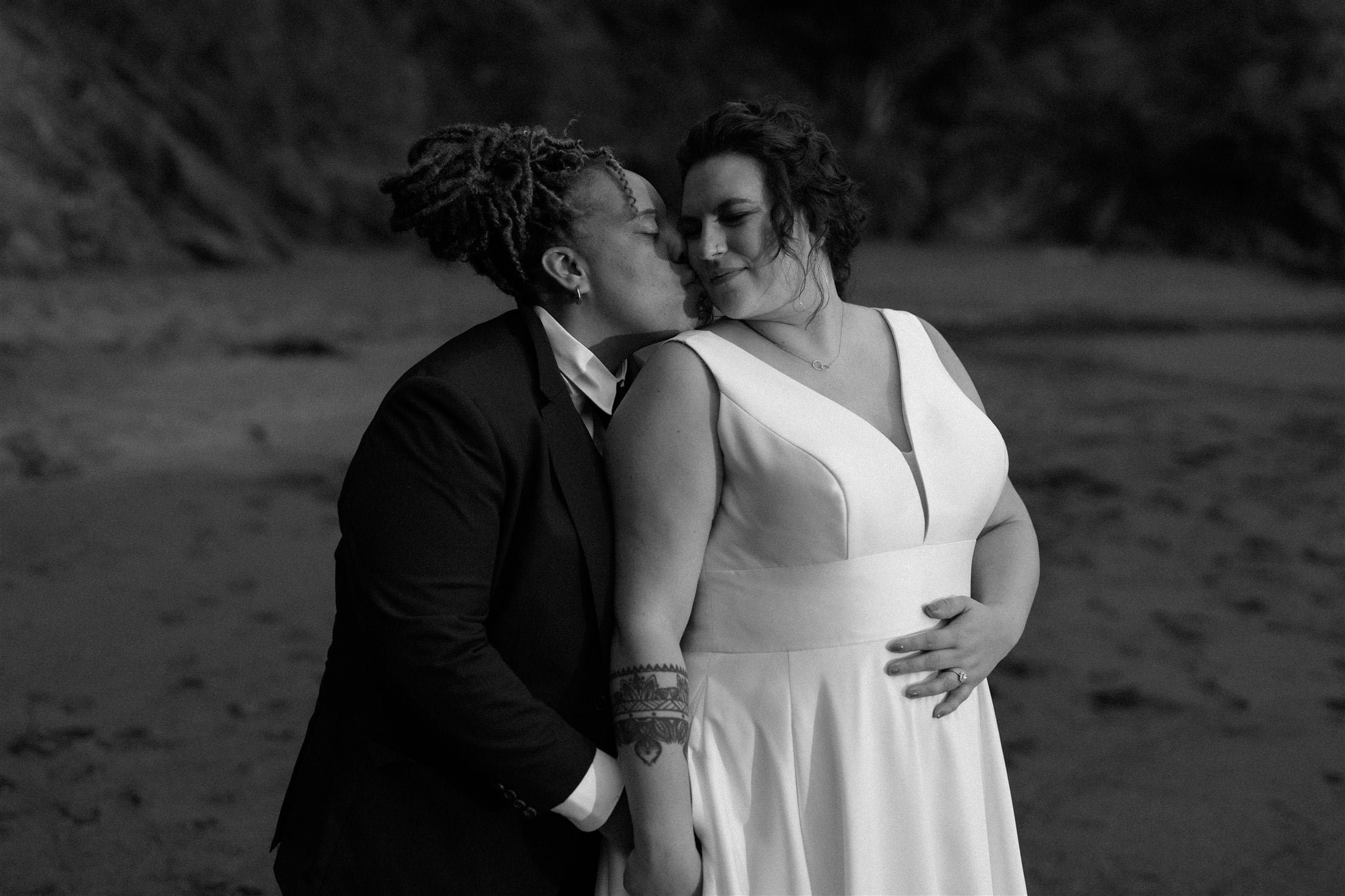 Two brides kiss during sunset portraits on the beach of their Southern Oregon Coast elopement