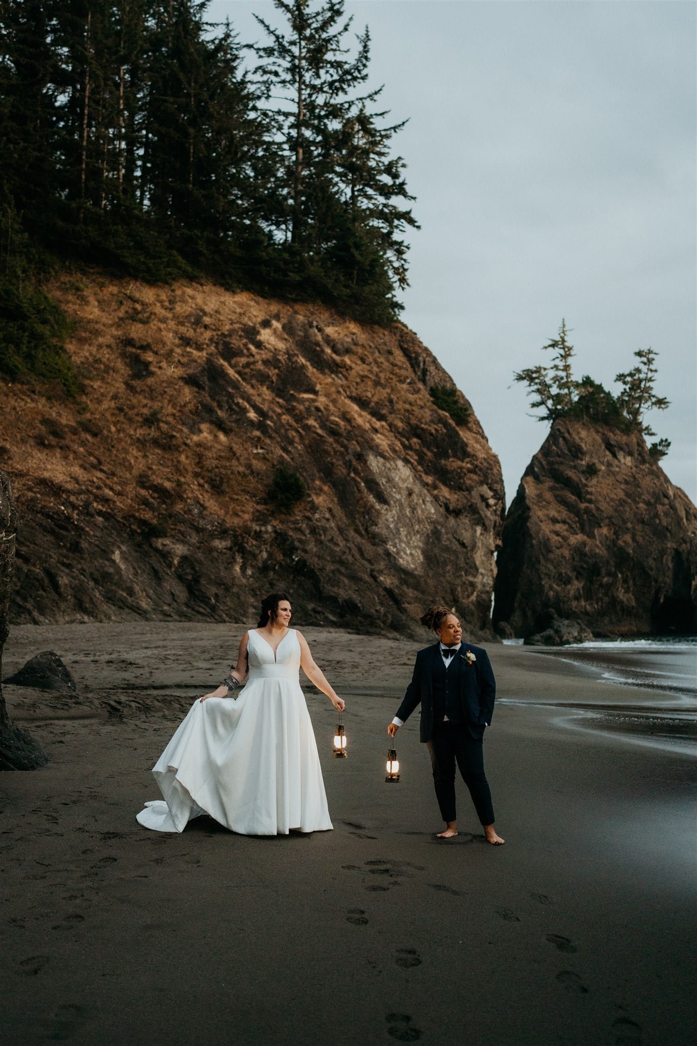 Two brides holding lanterns during their blue hour portraits on the Oregon Coast