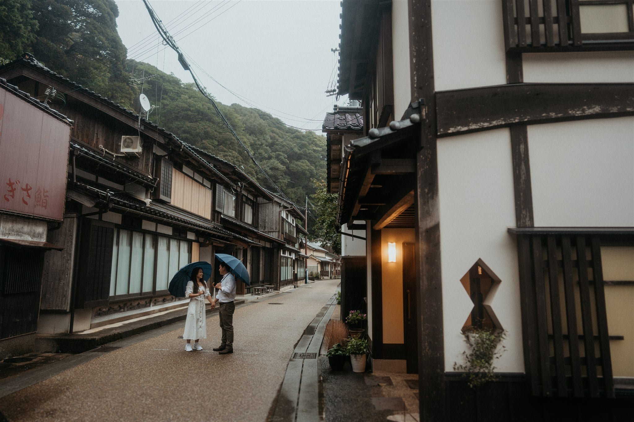 Bride and groom walking through Kyoto holding blue umbrellas on their elopement morning 
