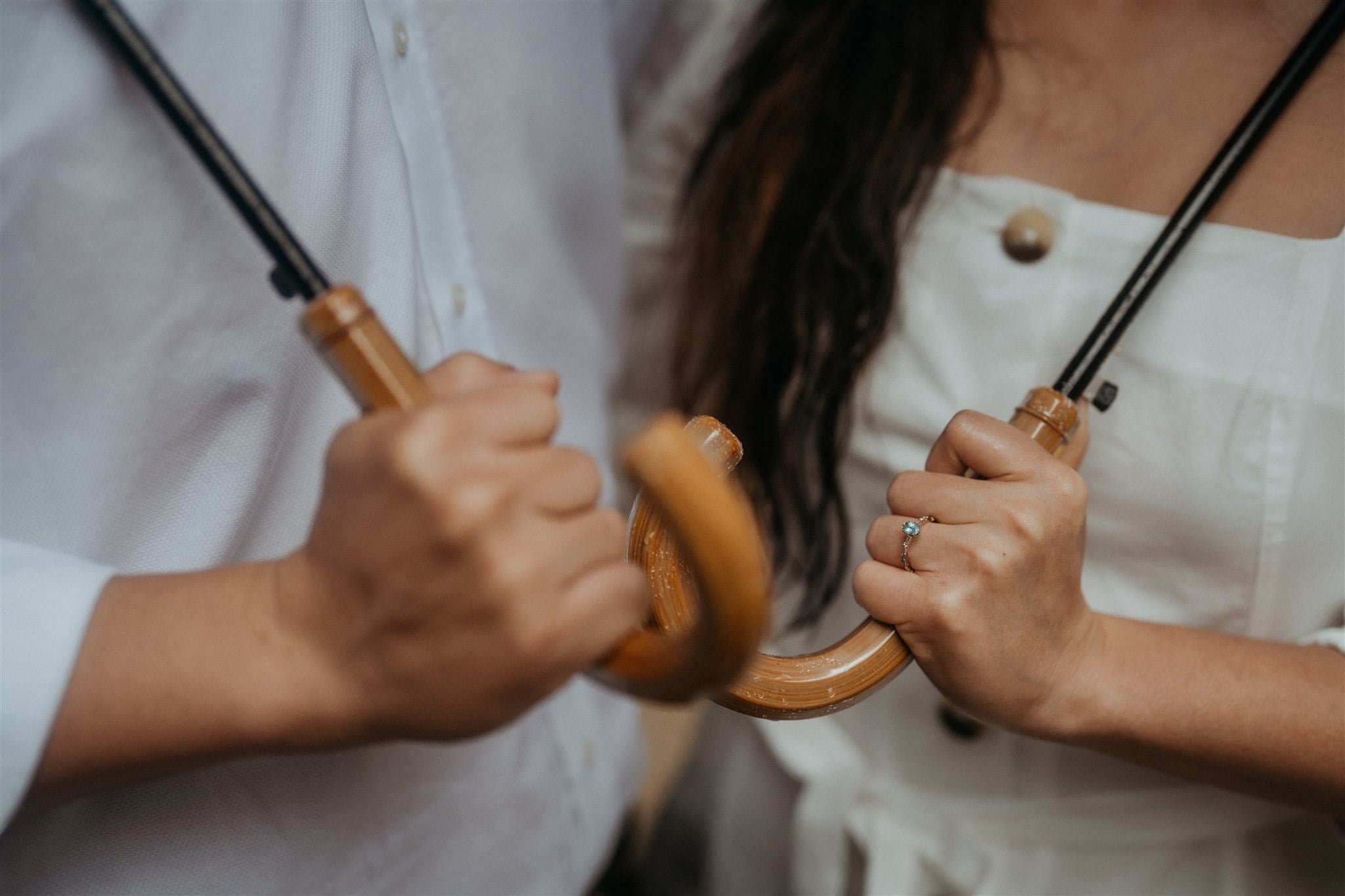 Bride and groom holding umbrellas with wood handles