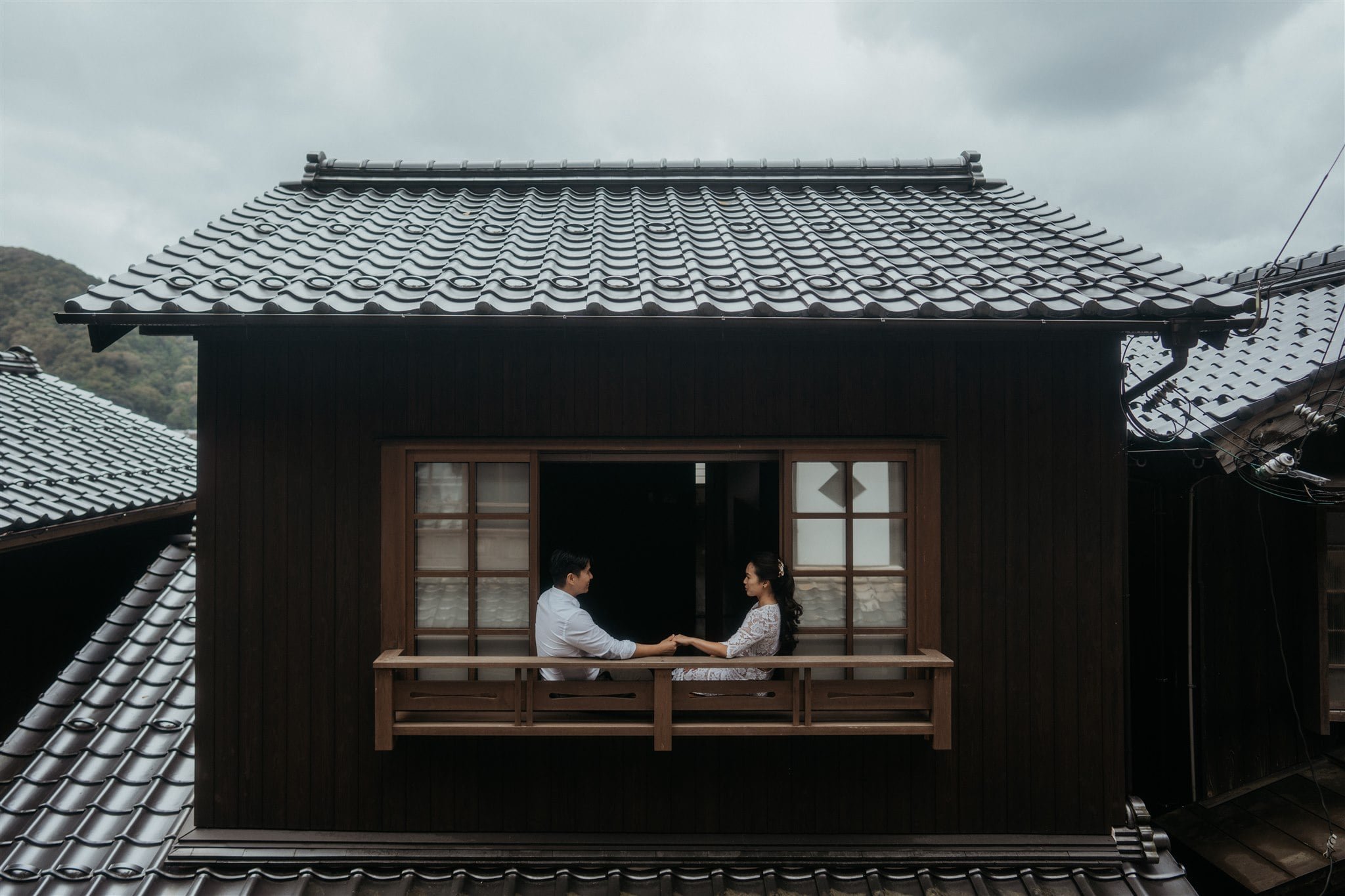 Bride and groom sitting in the window of their two story elopement cabin in Kyoto, Japan