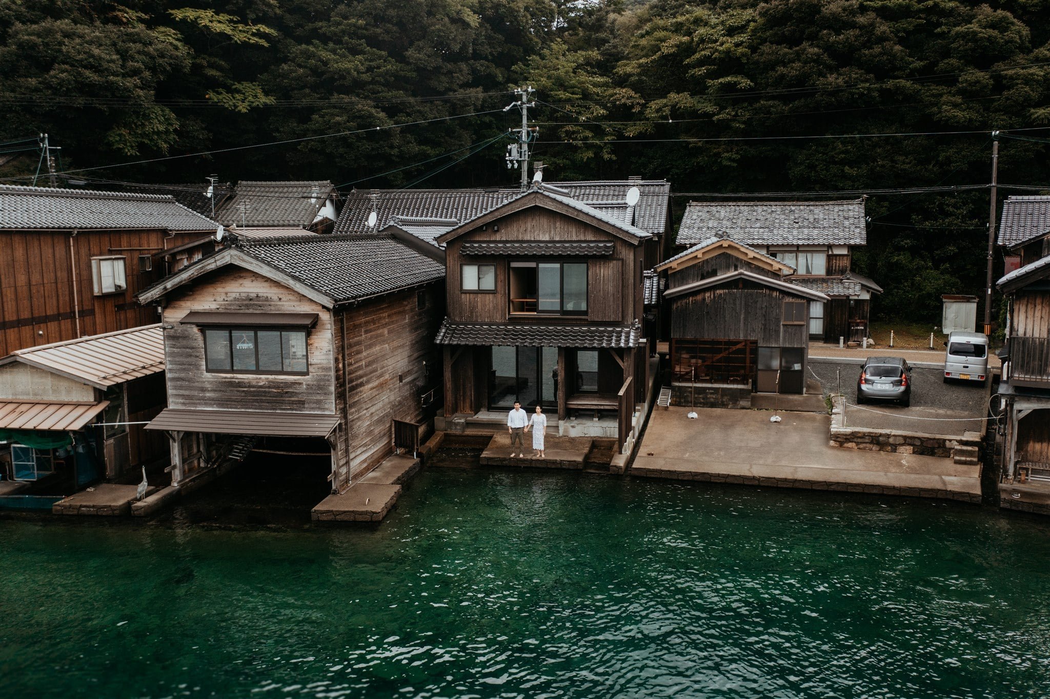 Bride and groom standing on the edge of the water in front of their elopement cabin in Kyoto, Japan