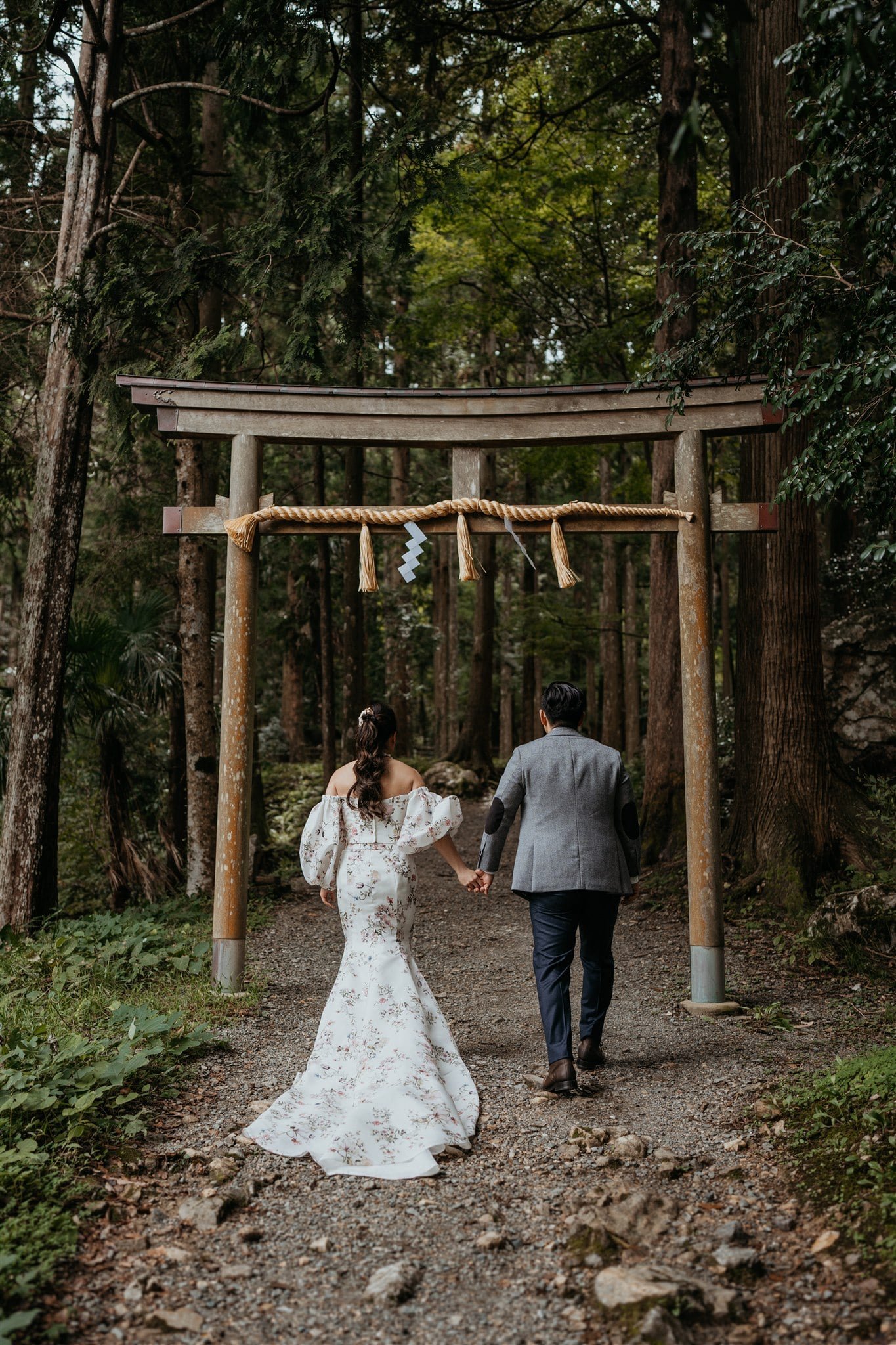 Bride and groom holding hands, walking into the forest during their elopement in Japan