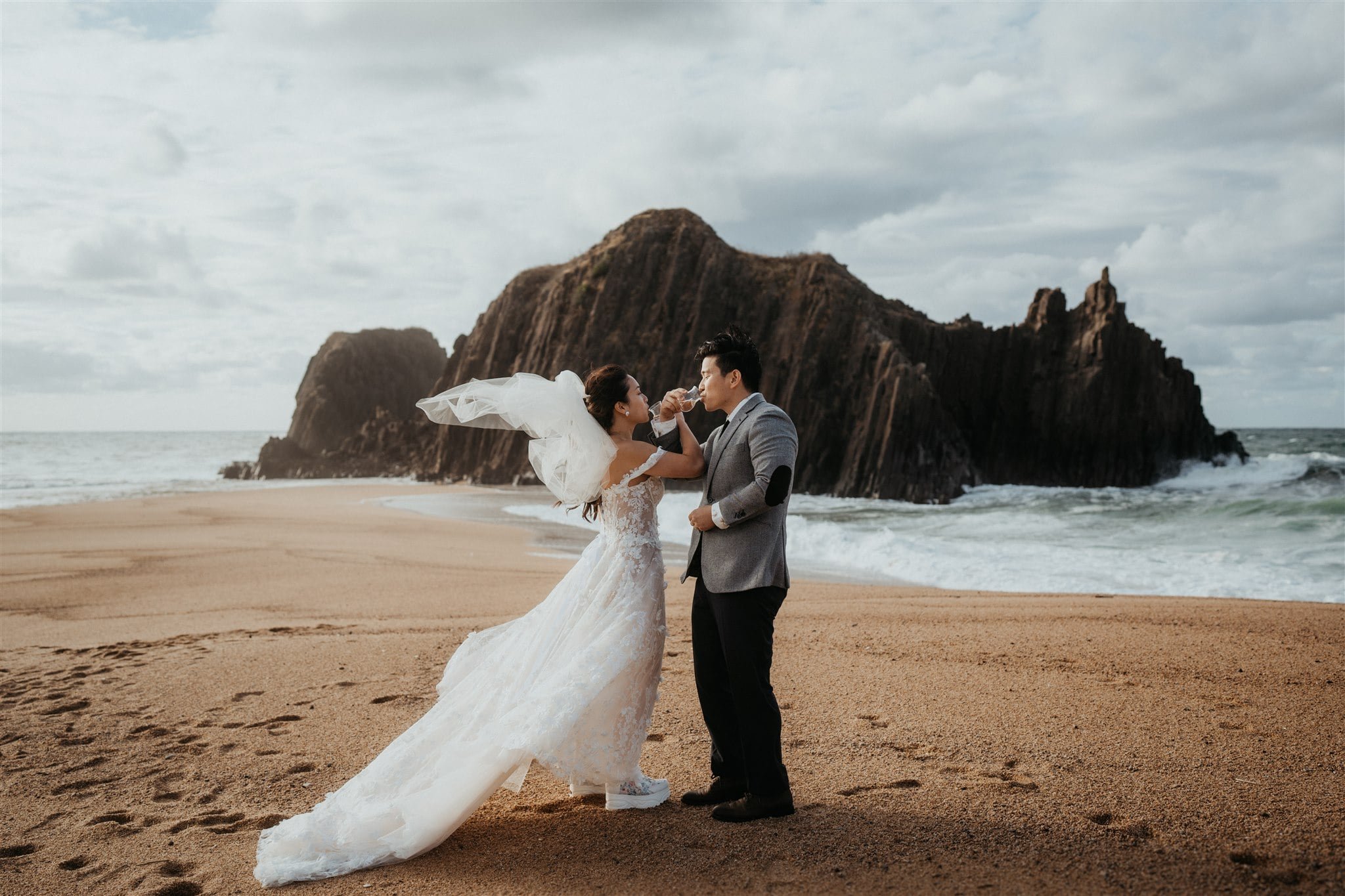 Bride and groom drink sake on the beach after their elopement ceremony