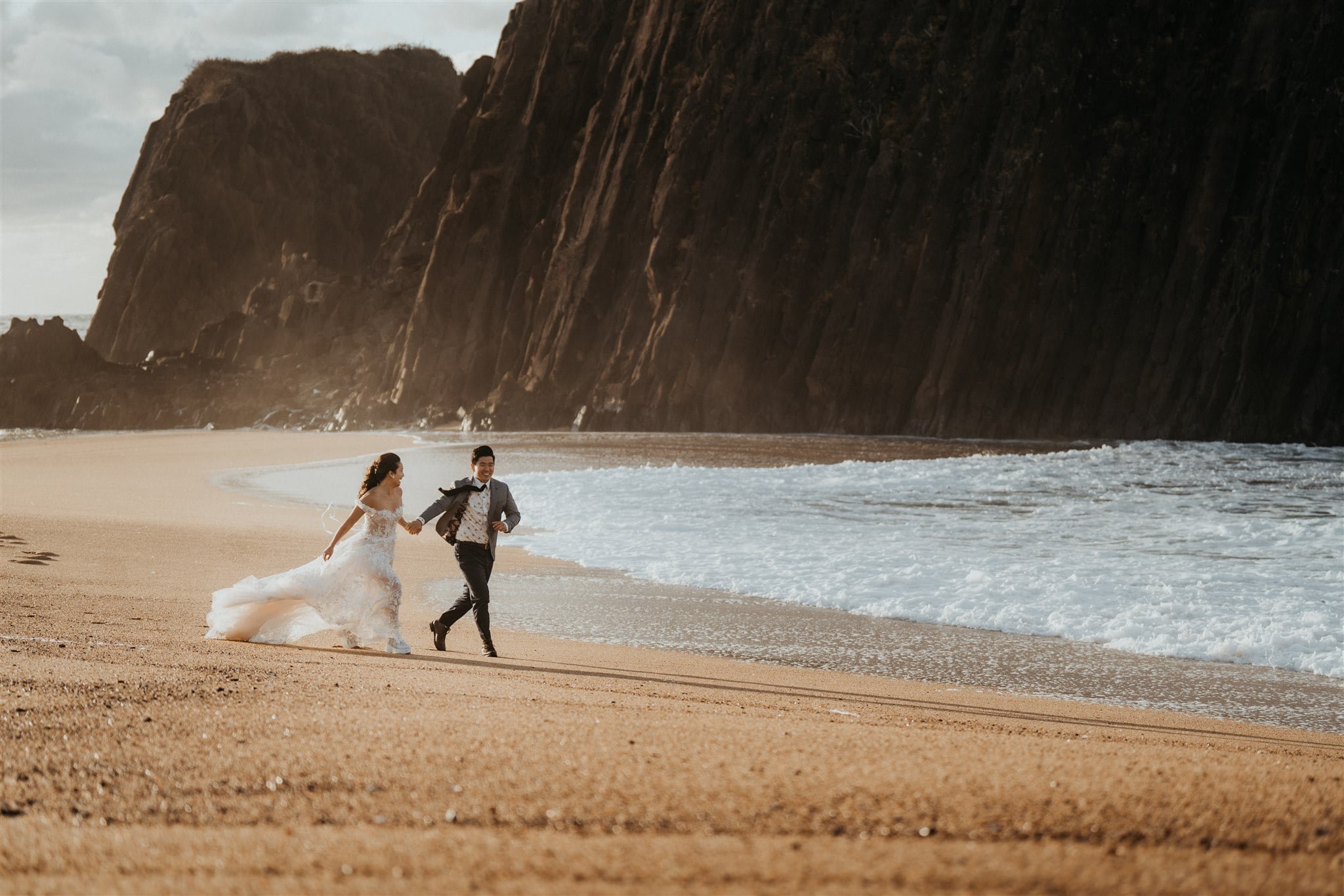 Bride and groom run across the beach during their Japan elopement portraits