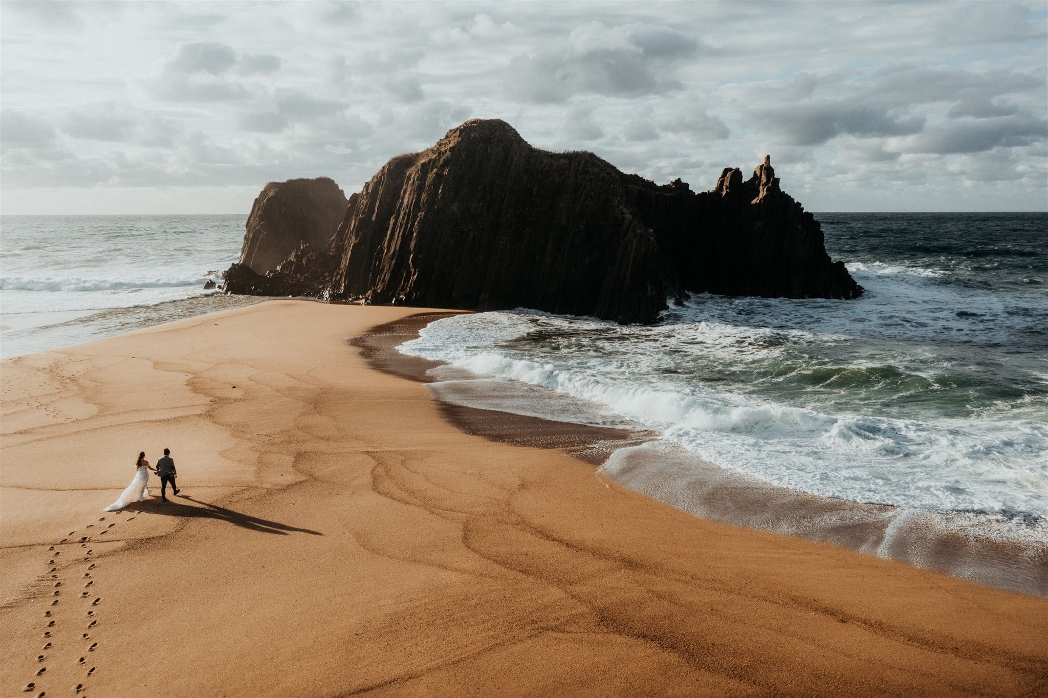 Bride and groom walk across the beach during their elopement in Japan