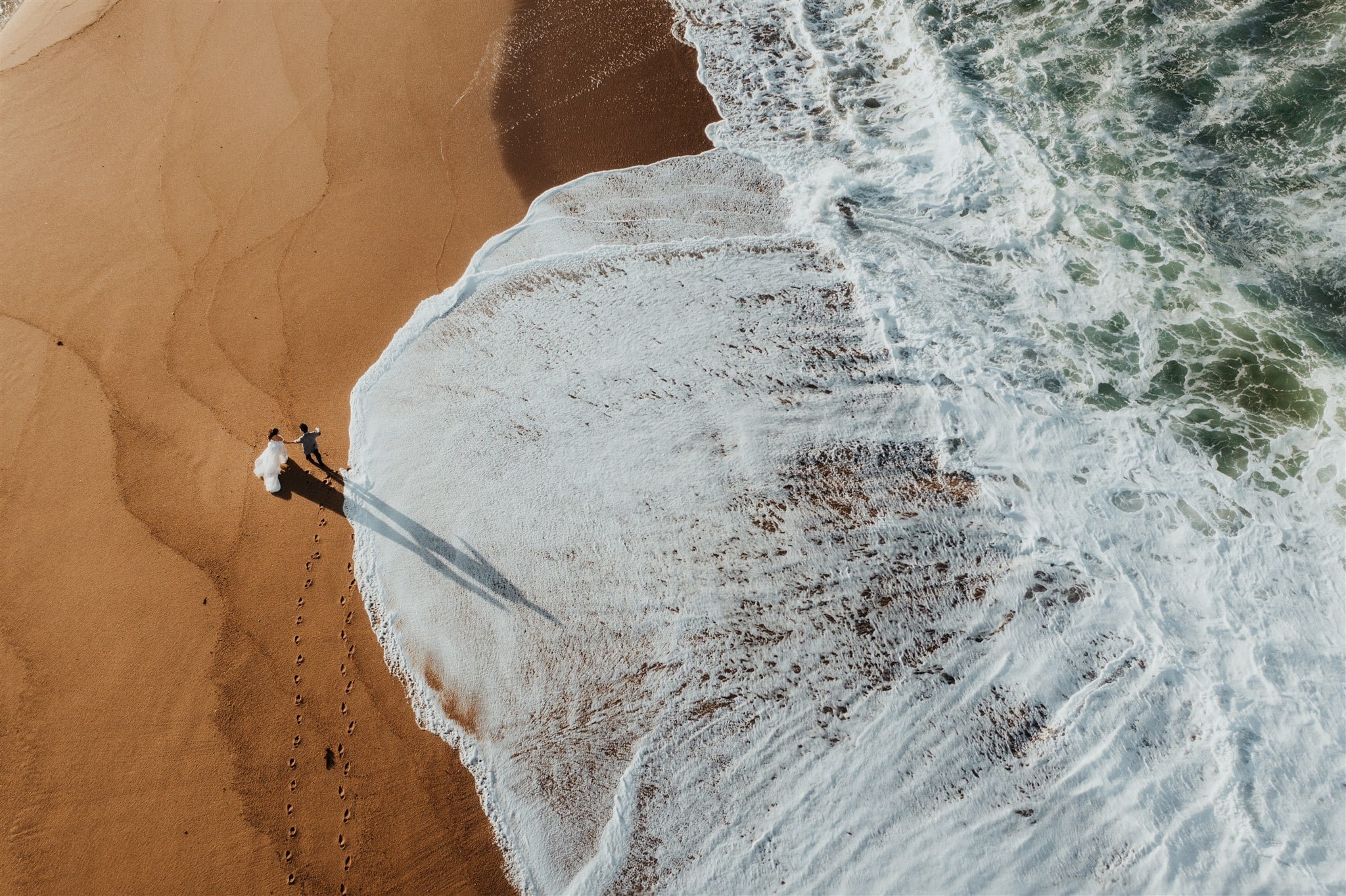 Bride and groom walk across the beach during their elopement in Japan