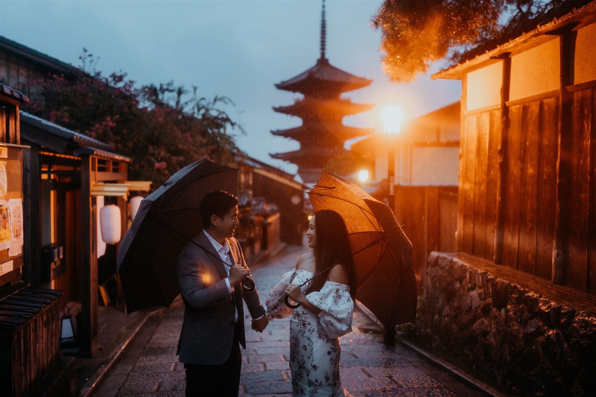 Bride and groom holding hands while walking with umbrellas during blue hour after their elopement in Japan