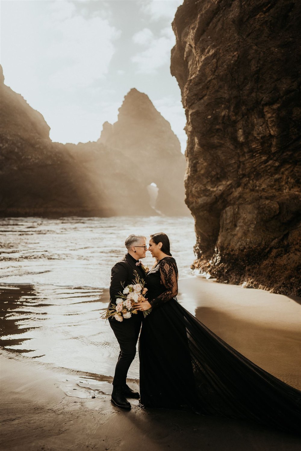 Brides wearing black wedding outfits on the beach during their Oregon Coast elopement
