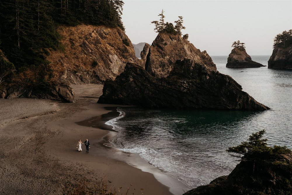 Bride and groom walking across the beach during their Southern Oregon Coast elopement