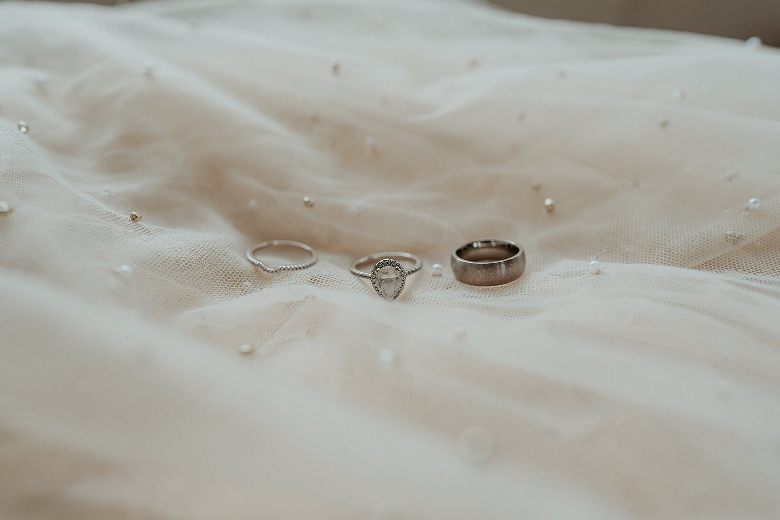 Three wedding rings sit atop white wedding dress