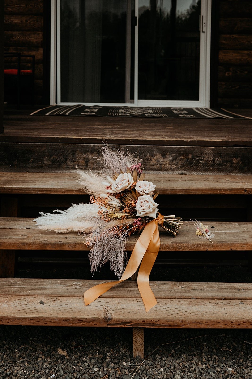 White and neutral boho wedding flowers sitting on the steps of cabin