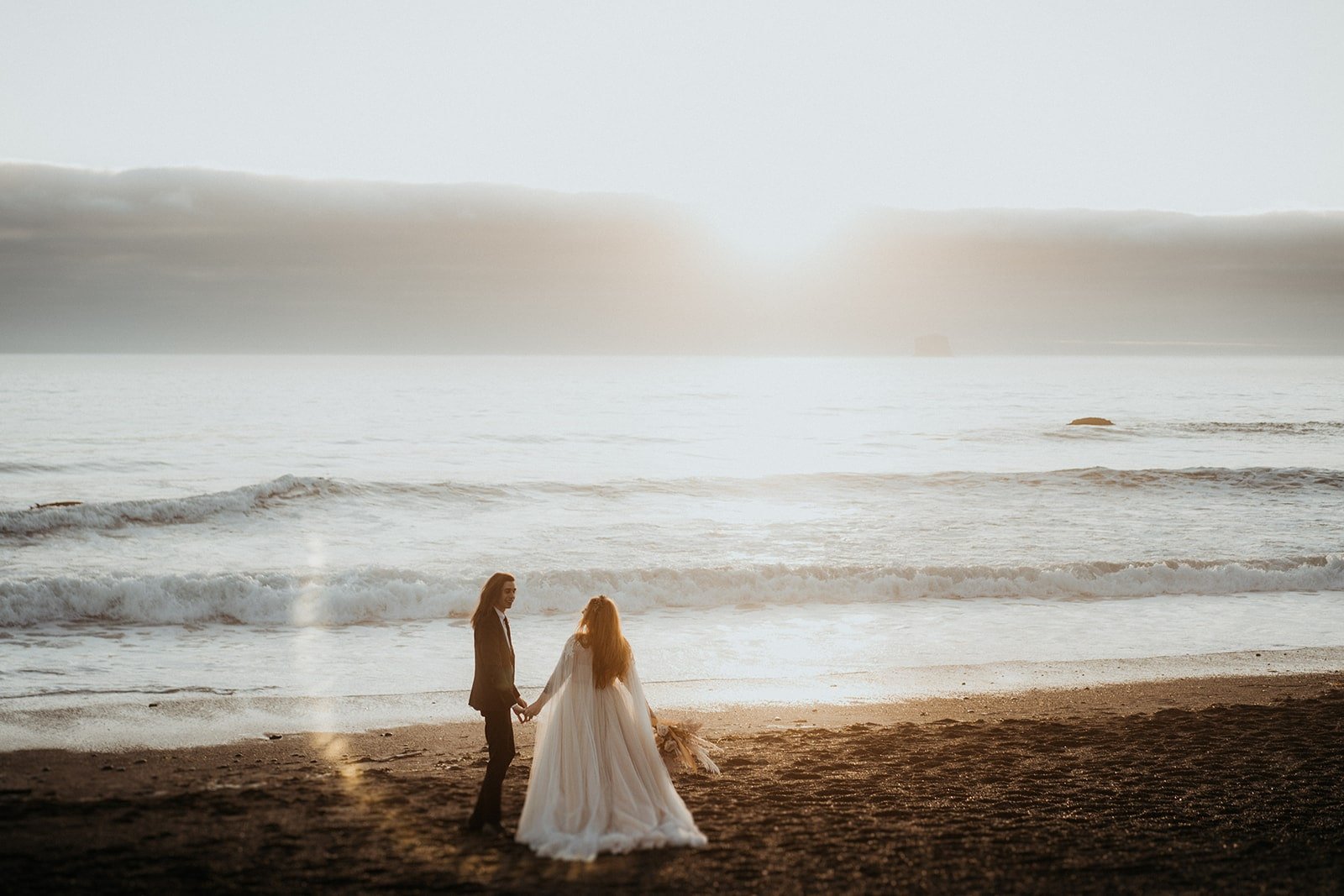Bride and groom walk across the sand during their elopement at Rialto Beach
