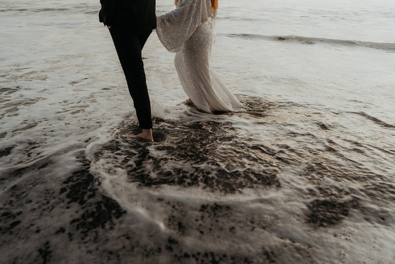 Bride and groom walk through the water during their elopement at Rialto Beach