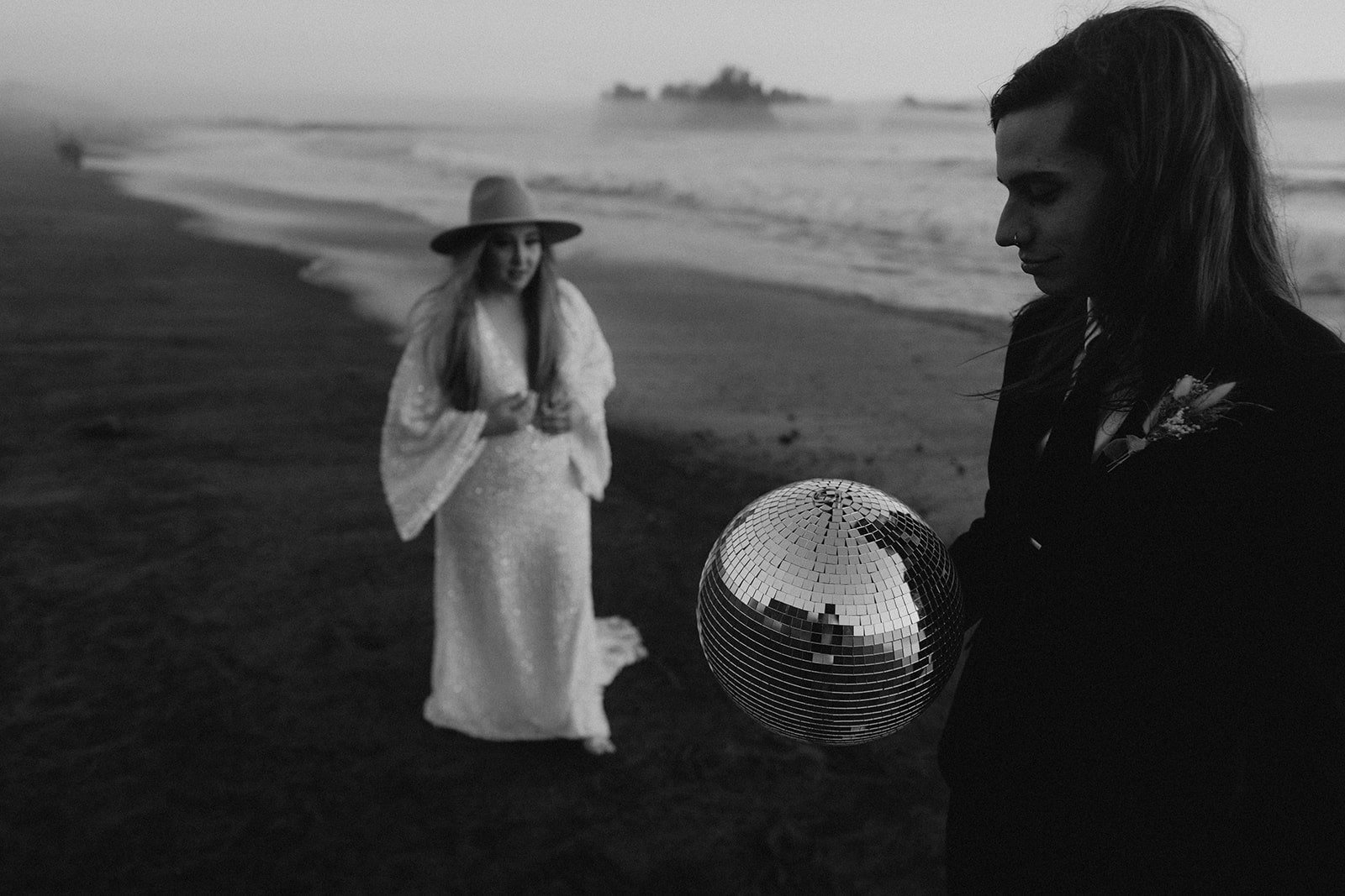 Bride and groom hold a disco ball during their elopement at Rialto Beach
