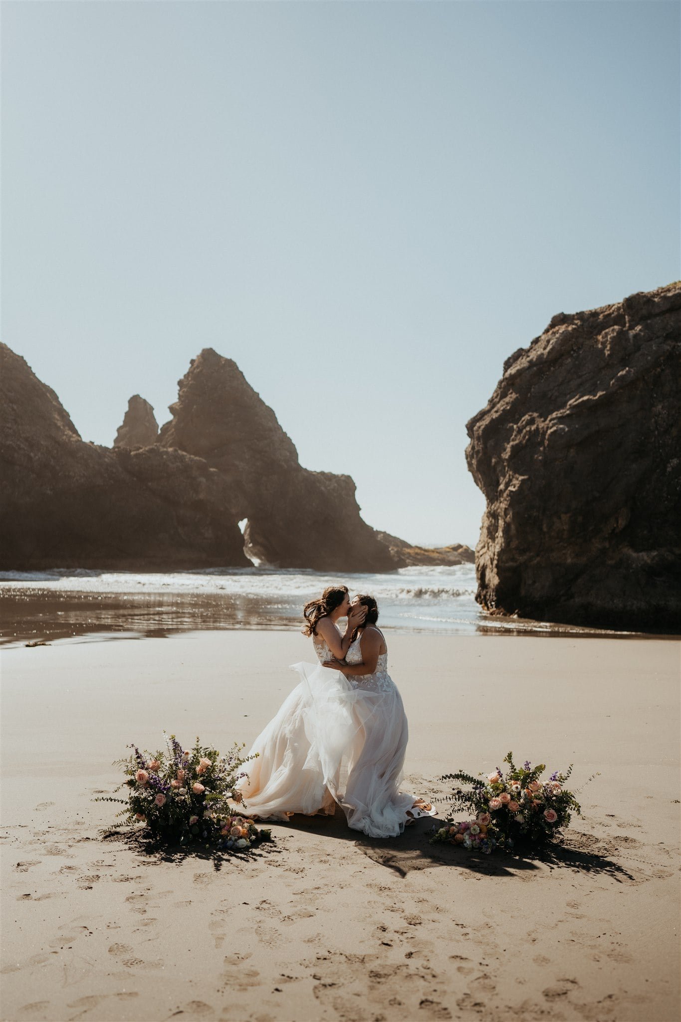 Brides exchange vows during their windy elopement ceremony on the beach on the Oregon Coast