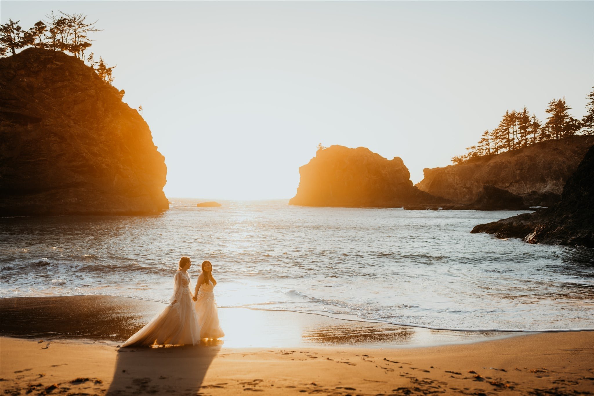 Brides walking across the beach during sunset portraits at elopement at Secret Beach, Oregon