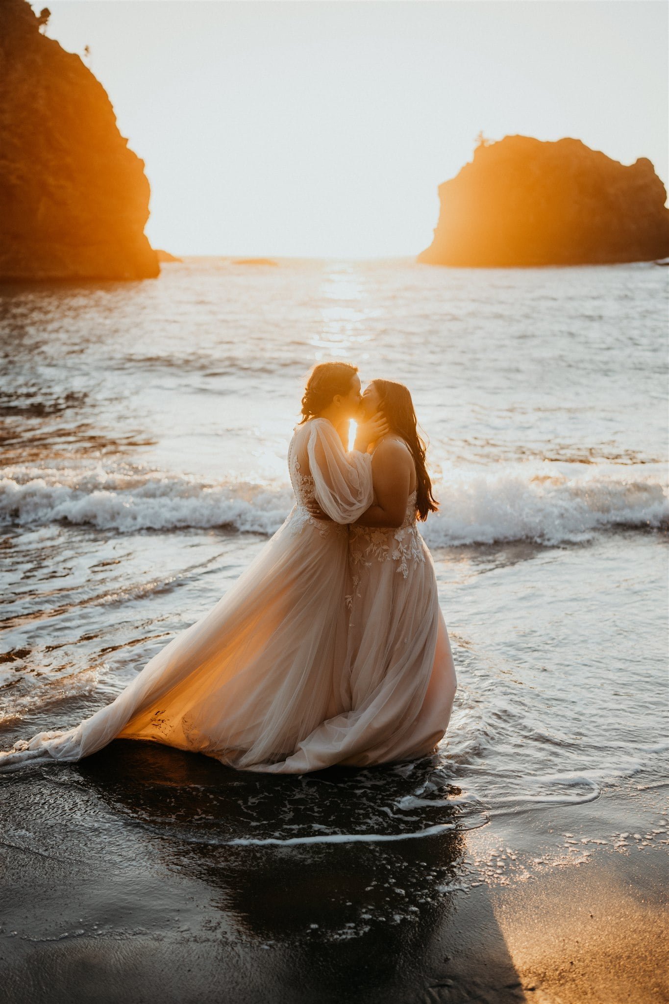 Brides kissing in the ocean during their sunset photos at Secret Beach, Oregon elopement