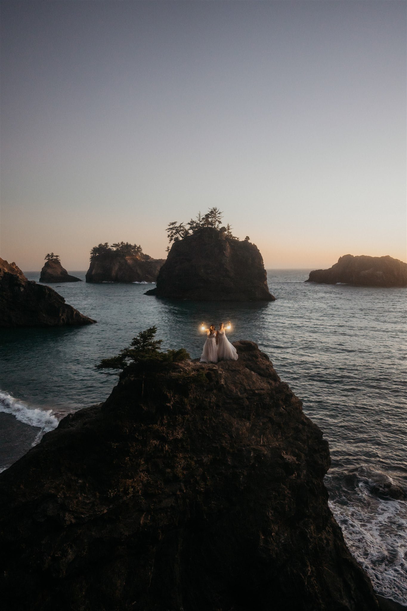 Two brides holding lanterns on the beach during blue hour portraits