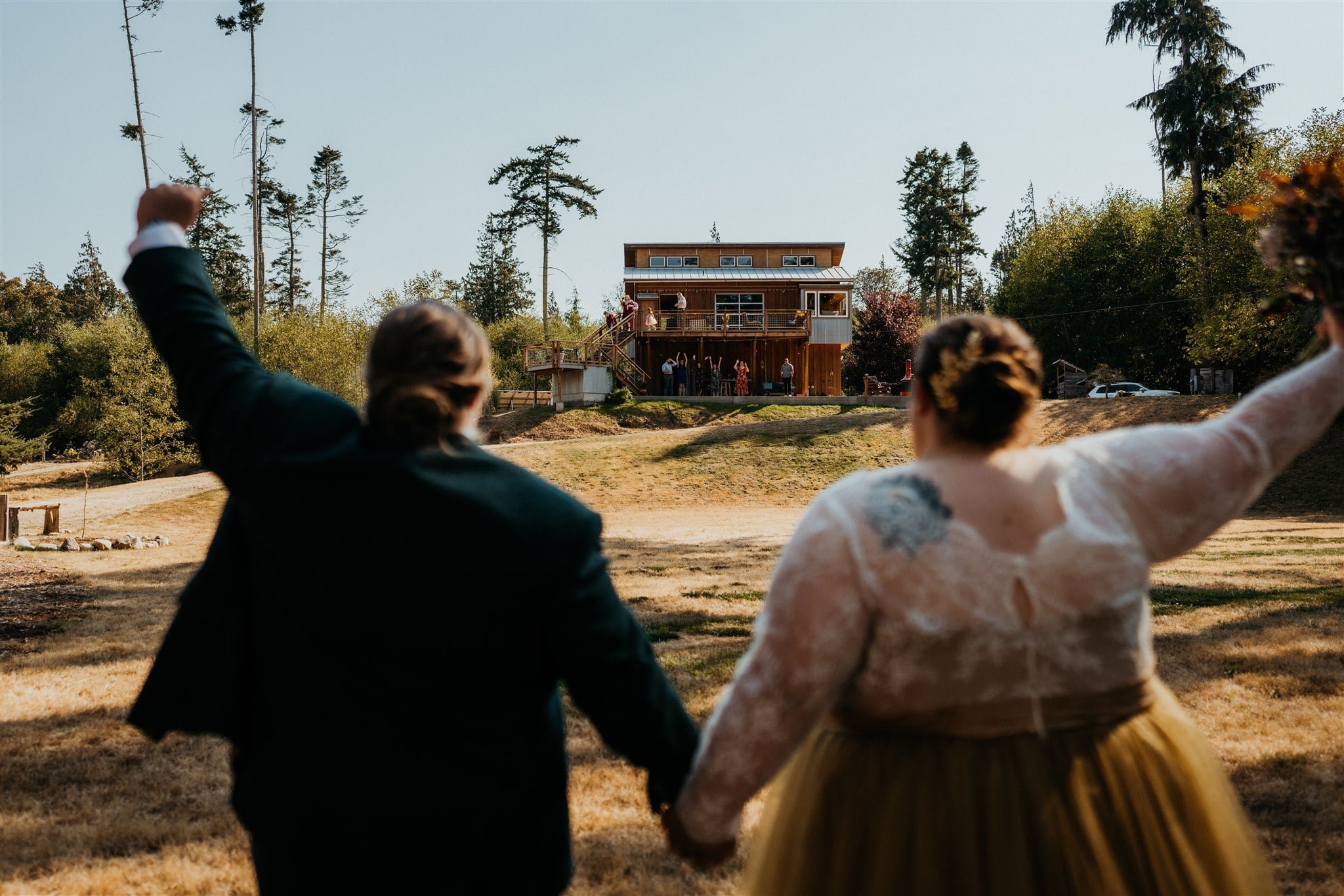 Brides wave to friends after their wedding first look in the forest 