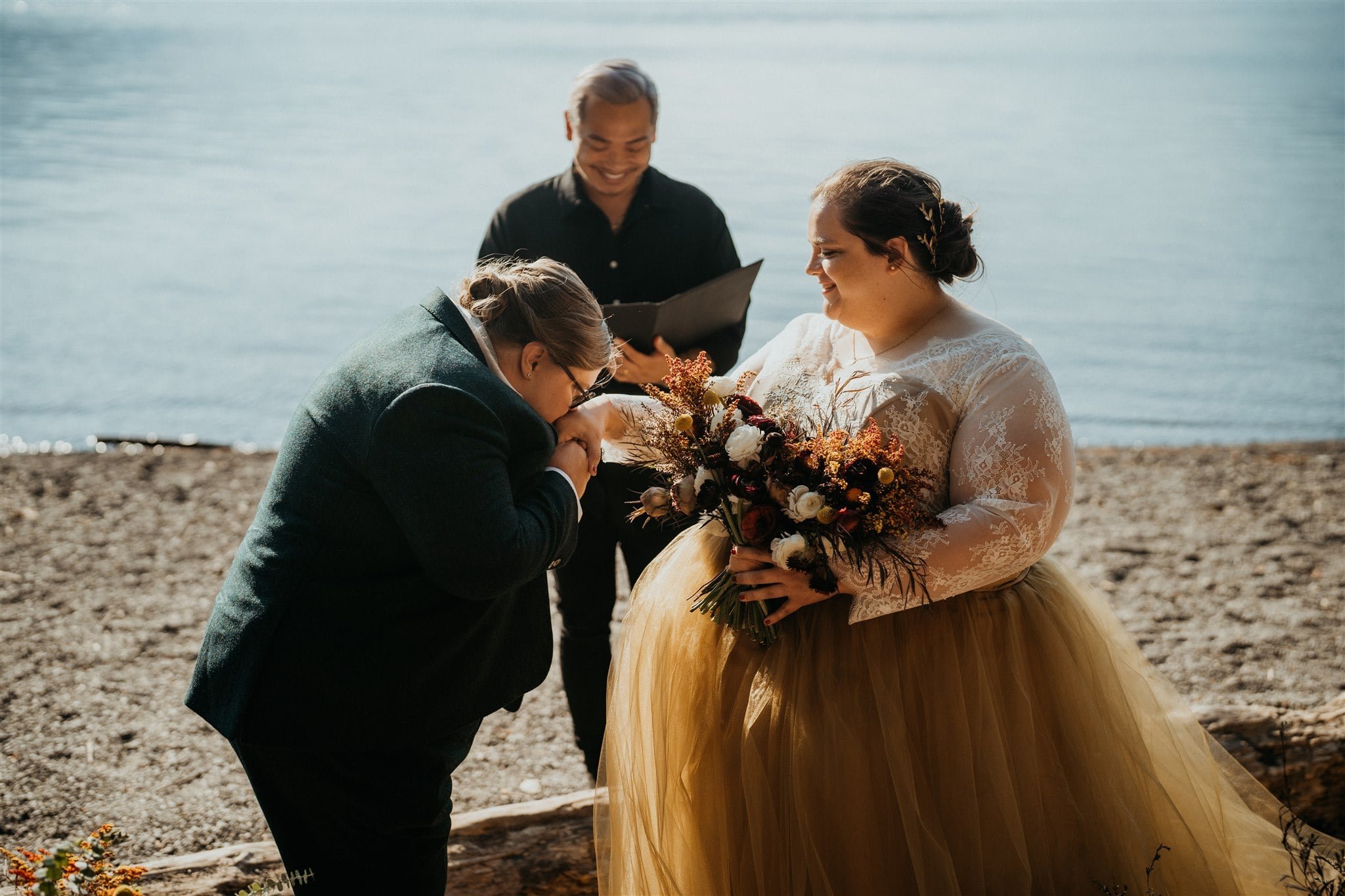 Bride kisses her bride's hand during Lake Crescent elopement ceremony