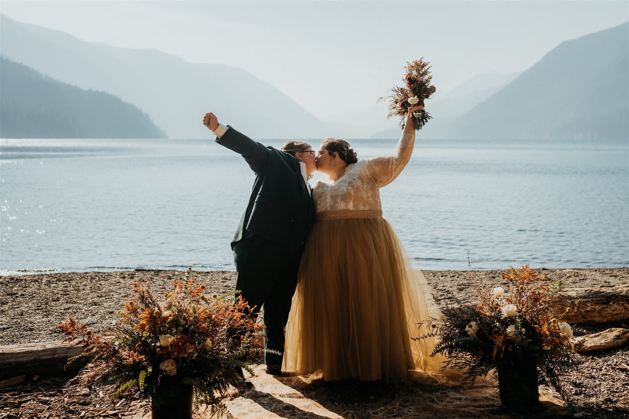 Brides cheer after their outdoor elopement ceremony at Lake Crescent