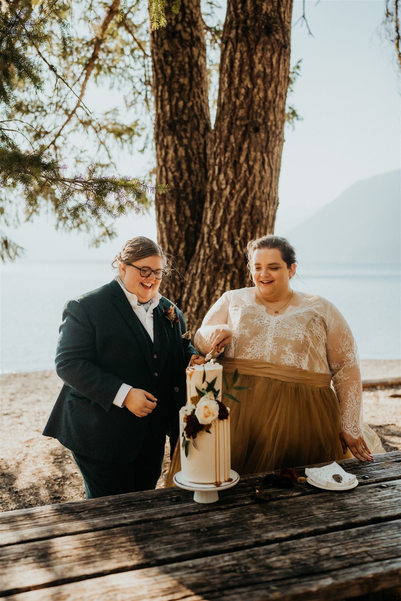 Brides cut into white two tier wedding cake at Lake Crescent elopement