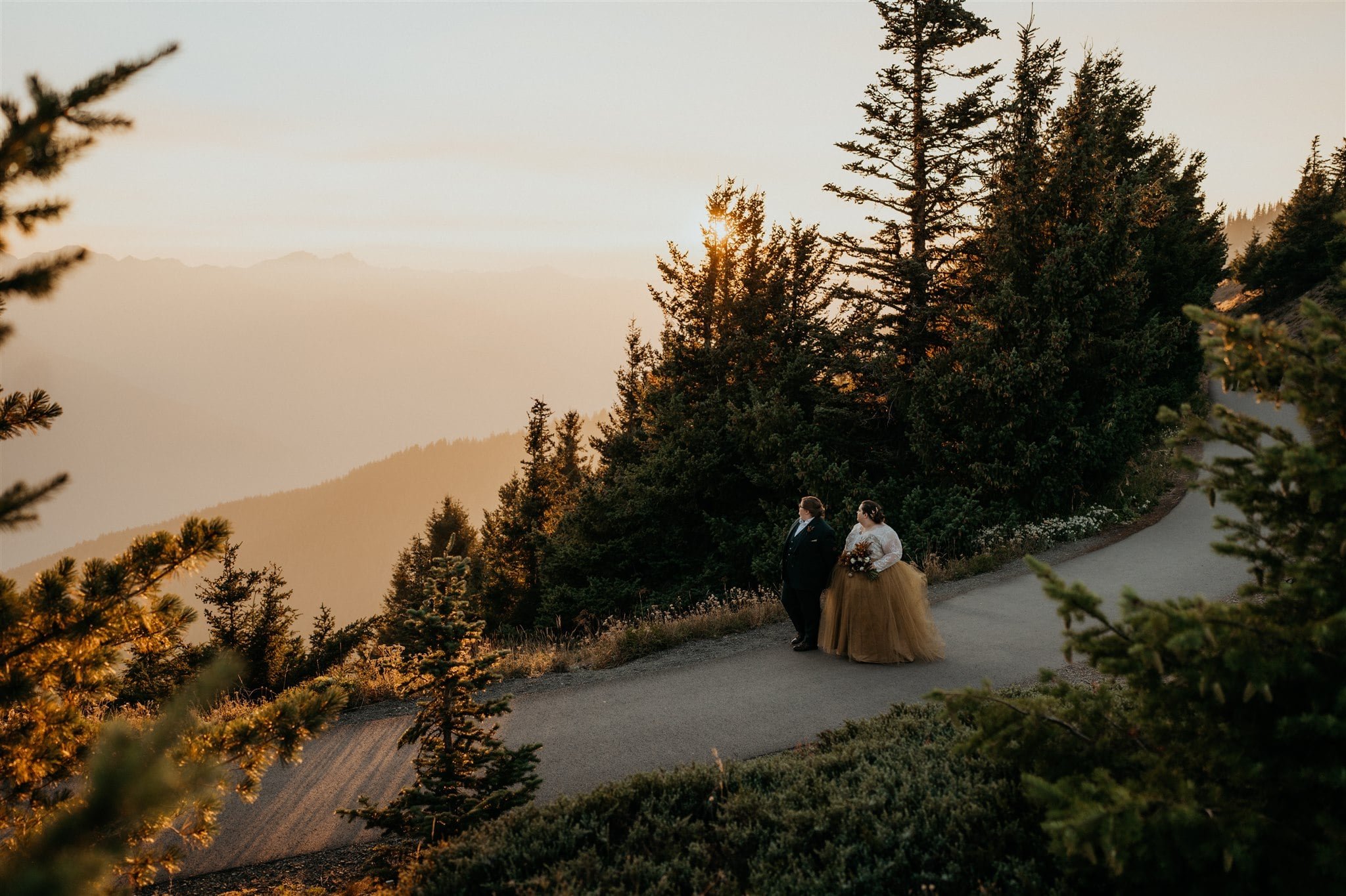 Brides hold hands while walking down a trail at Olympic National Park elopement