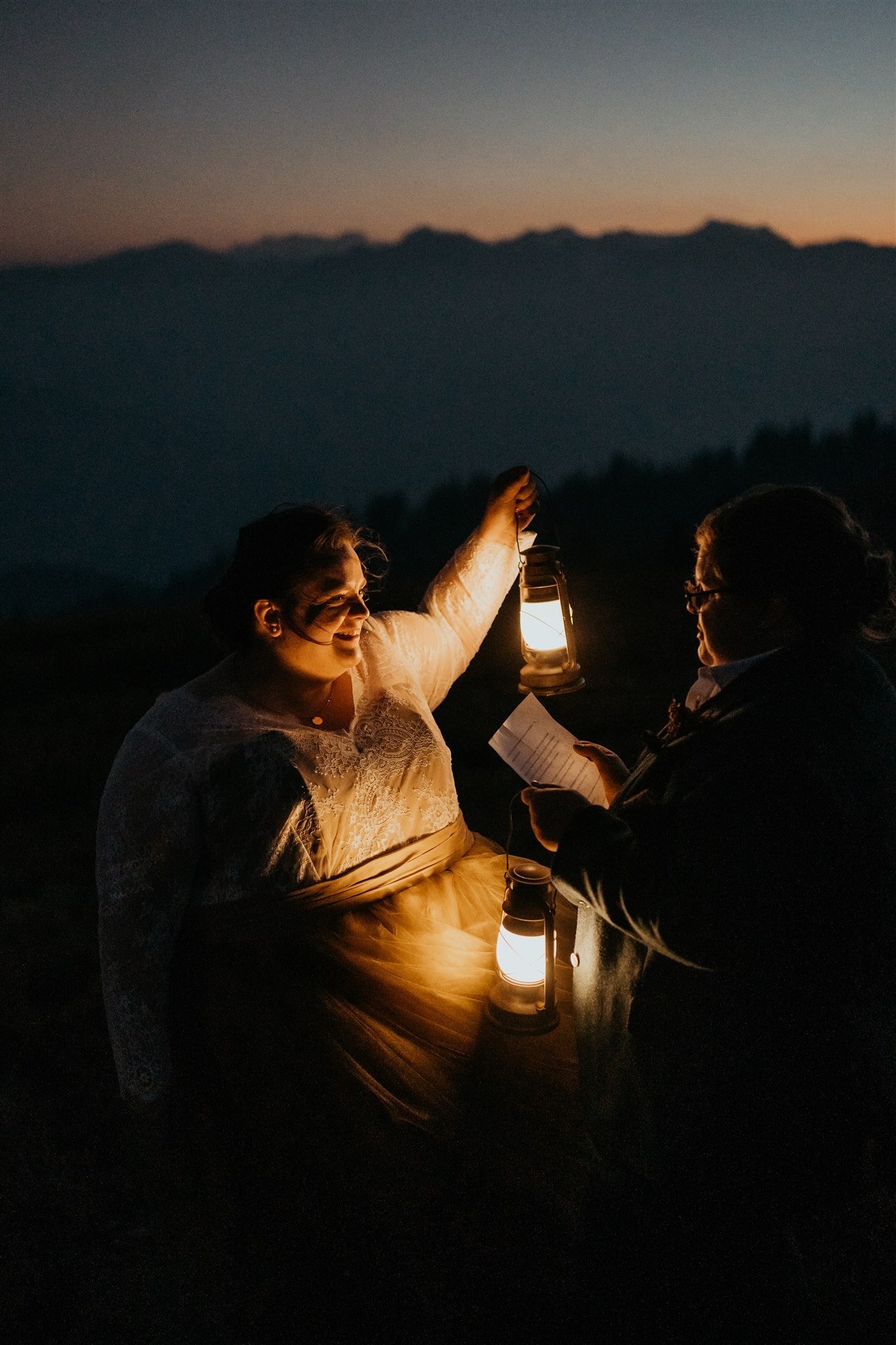 Brides reading private vows by lantern light at Olympic National Park elopement