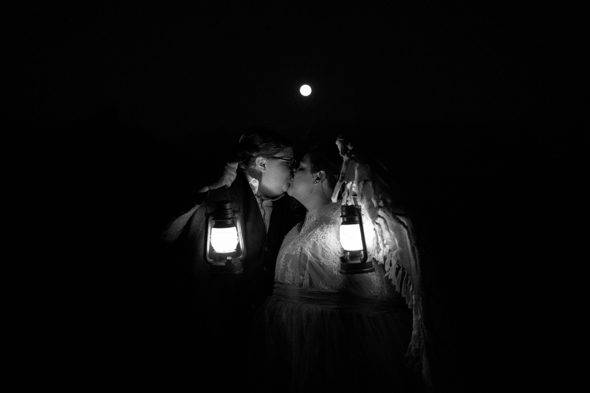 Brides kiss while holding lanterns at blue hour in Olympic National Park