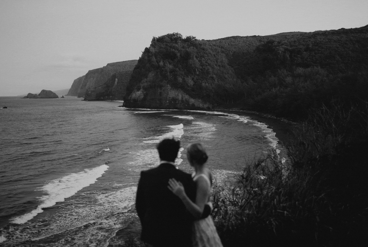 Bride and groom standing and looking out at the ocean at the end of their Big Island elopement