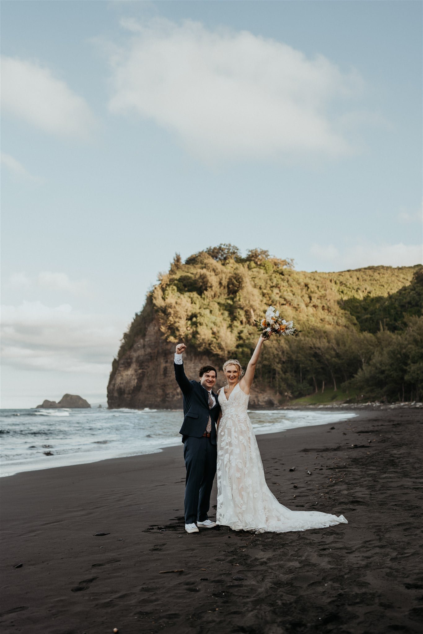 Bride and groom cheer after their Big Island elopement ceremony on a black sand beach