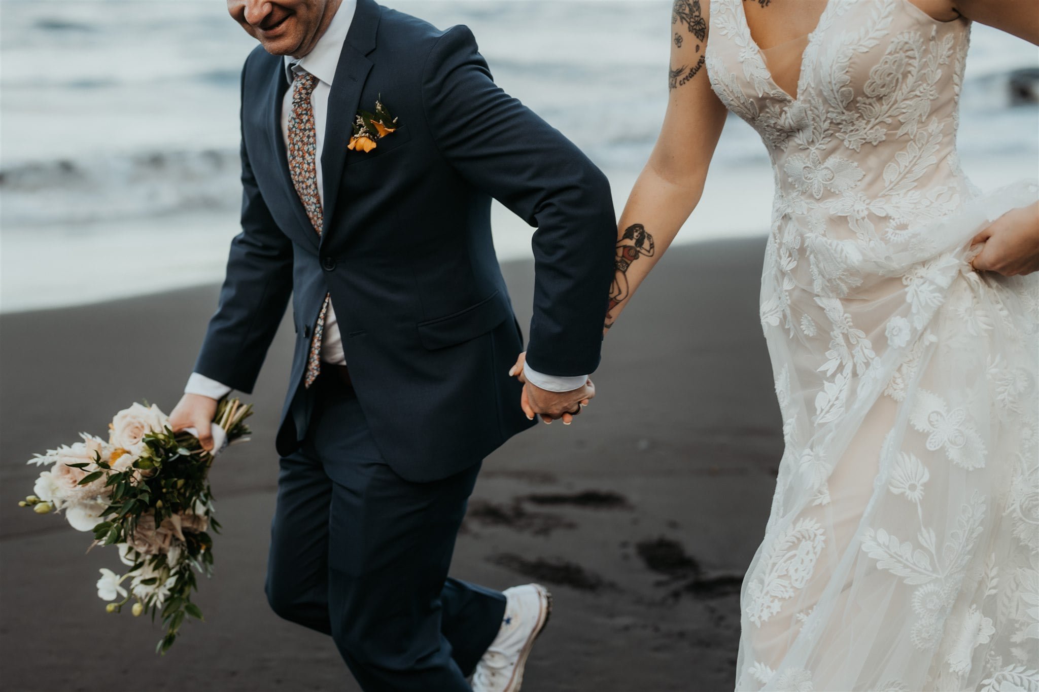 Bride and groom hold hands while running across the beach for their elopement in Hawaii