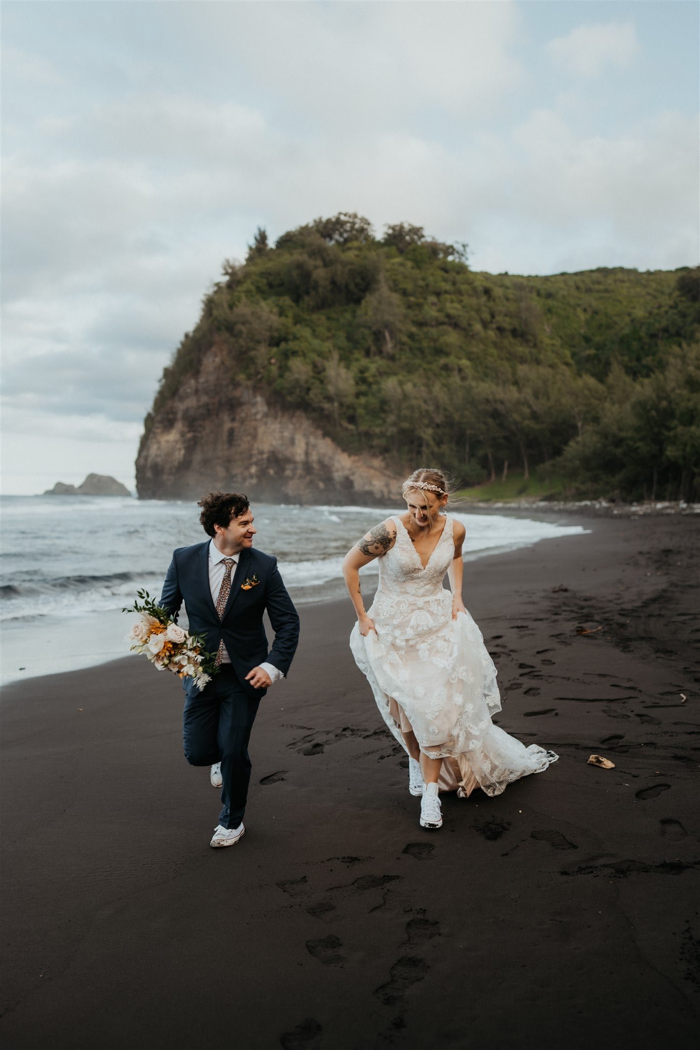 Bride and groom run across the beach while they elope on the Big Island