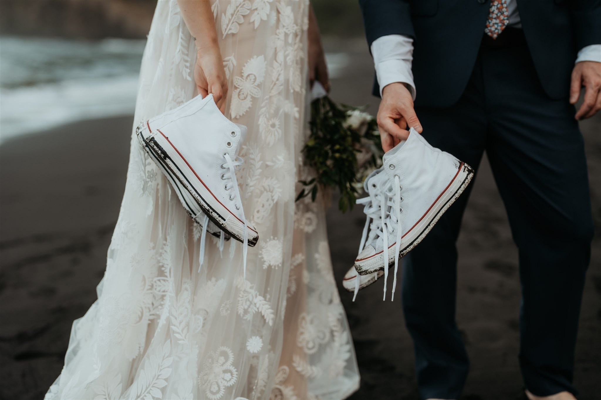 Bride and groom holding converse on the black sand beach for their Hawaii elopement