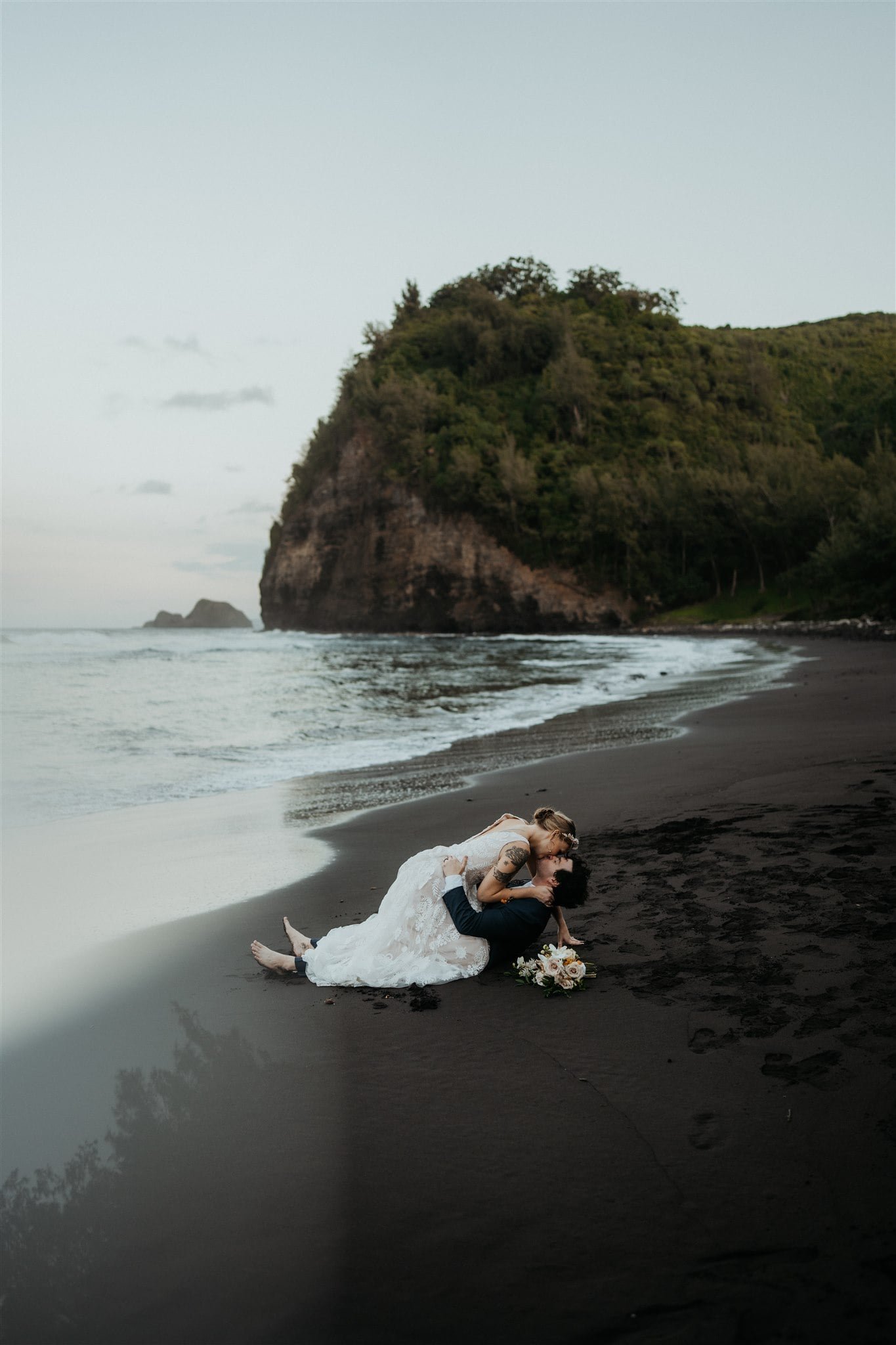 Bride and groom kiss on the black sand beach during their Big Island elopement
