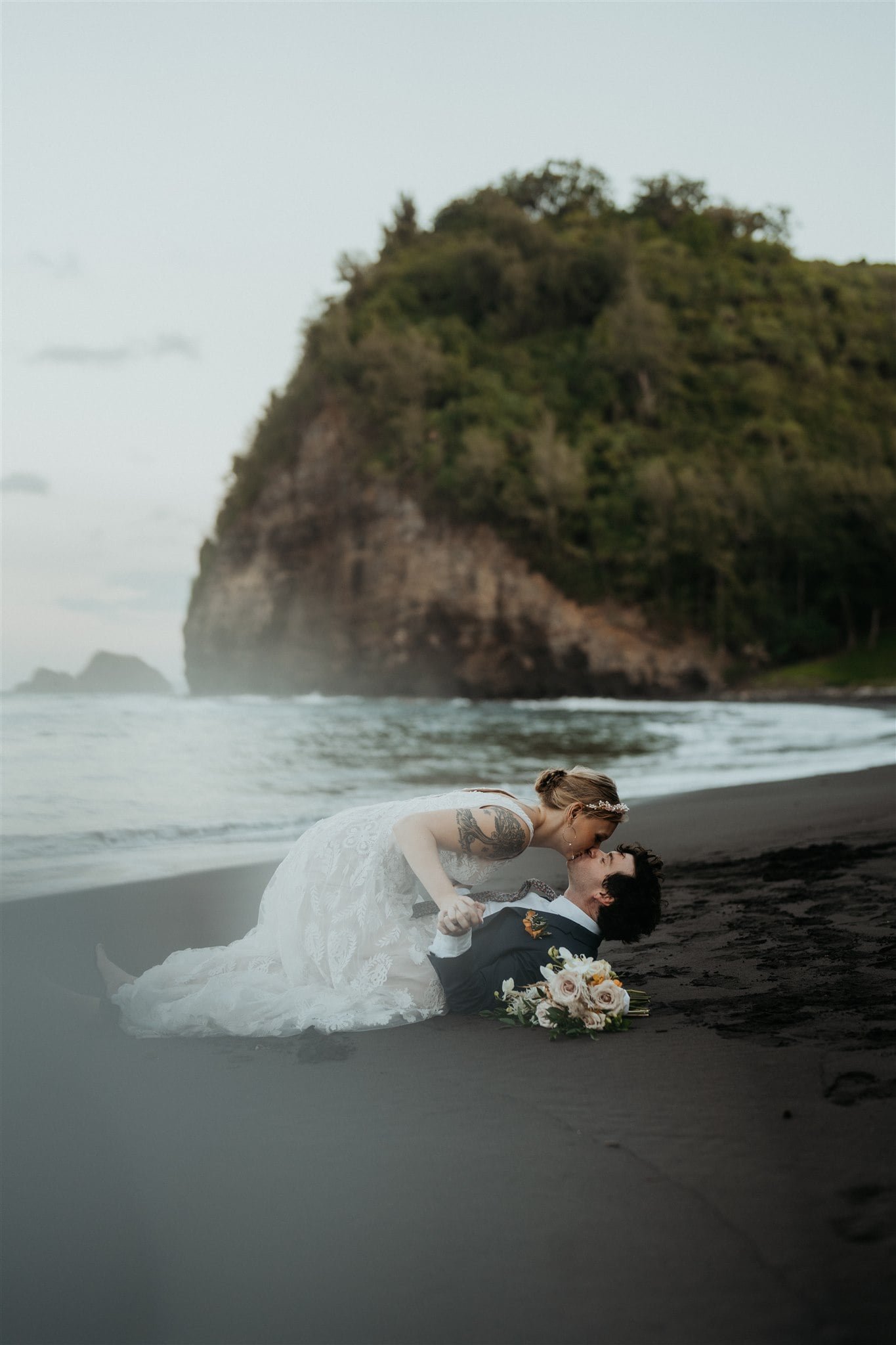 Bride and groom kiss on the black sand beach during their Big Island elopement