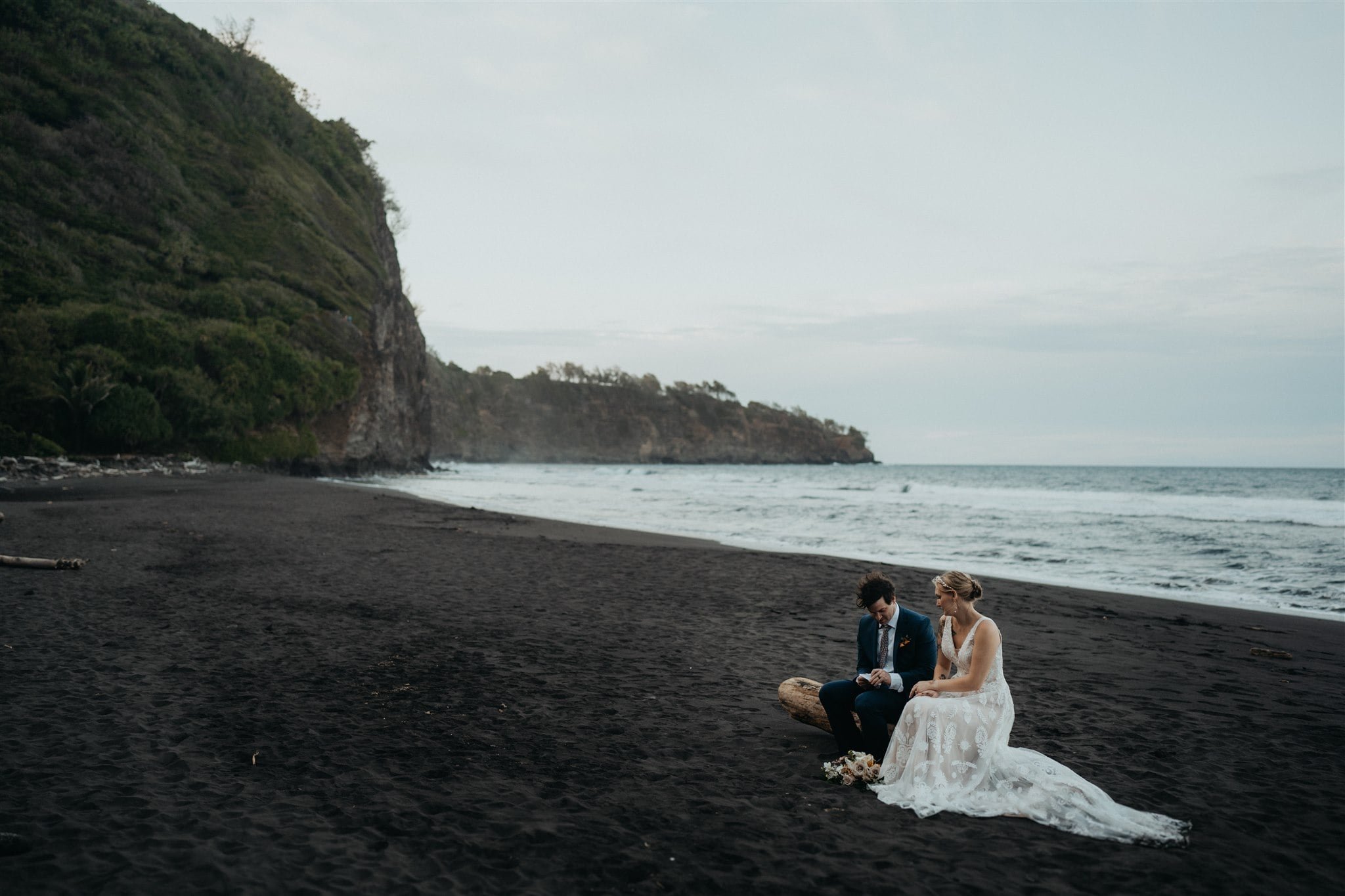 Bride and groom read letters on the beach at their Big Island elopement